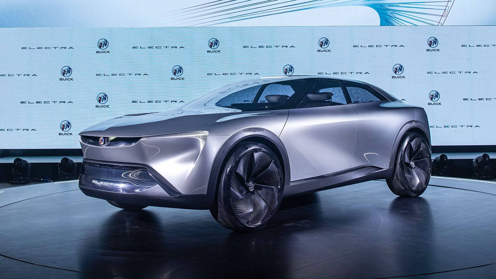 Buick 桌布 壁紙 — 在帶有品牌背景的車展旋轉平台上，一輛時尚的銀色未來感Buick Electra概念車。