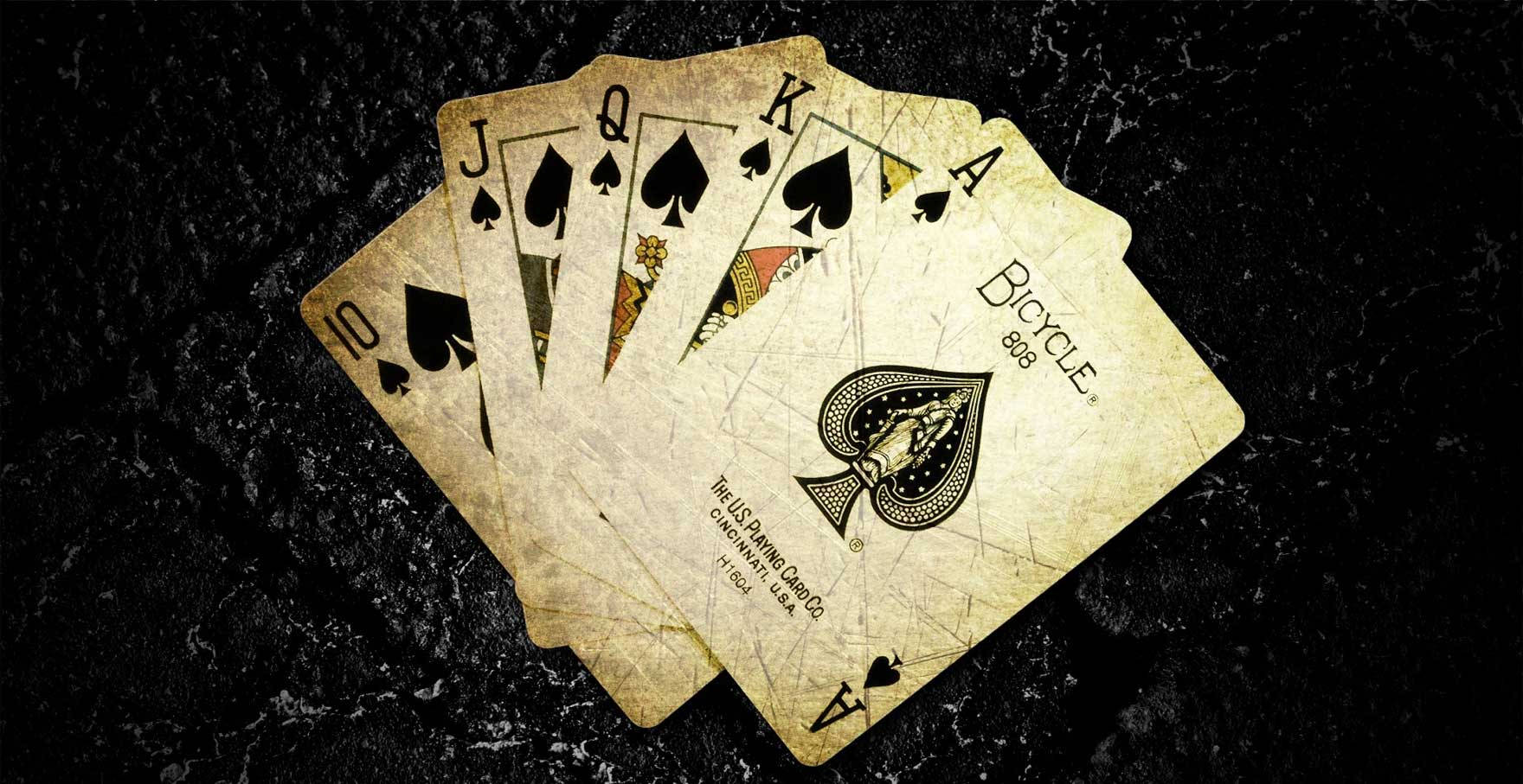 Playing Cards 桌布 壁紙 — 在帶有復古垃圾效果的深色紋理表面上展開的磨損黑桃撲克牌扇。