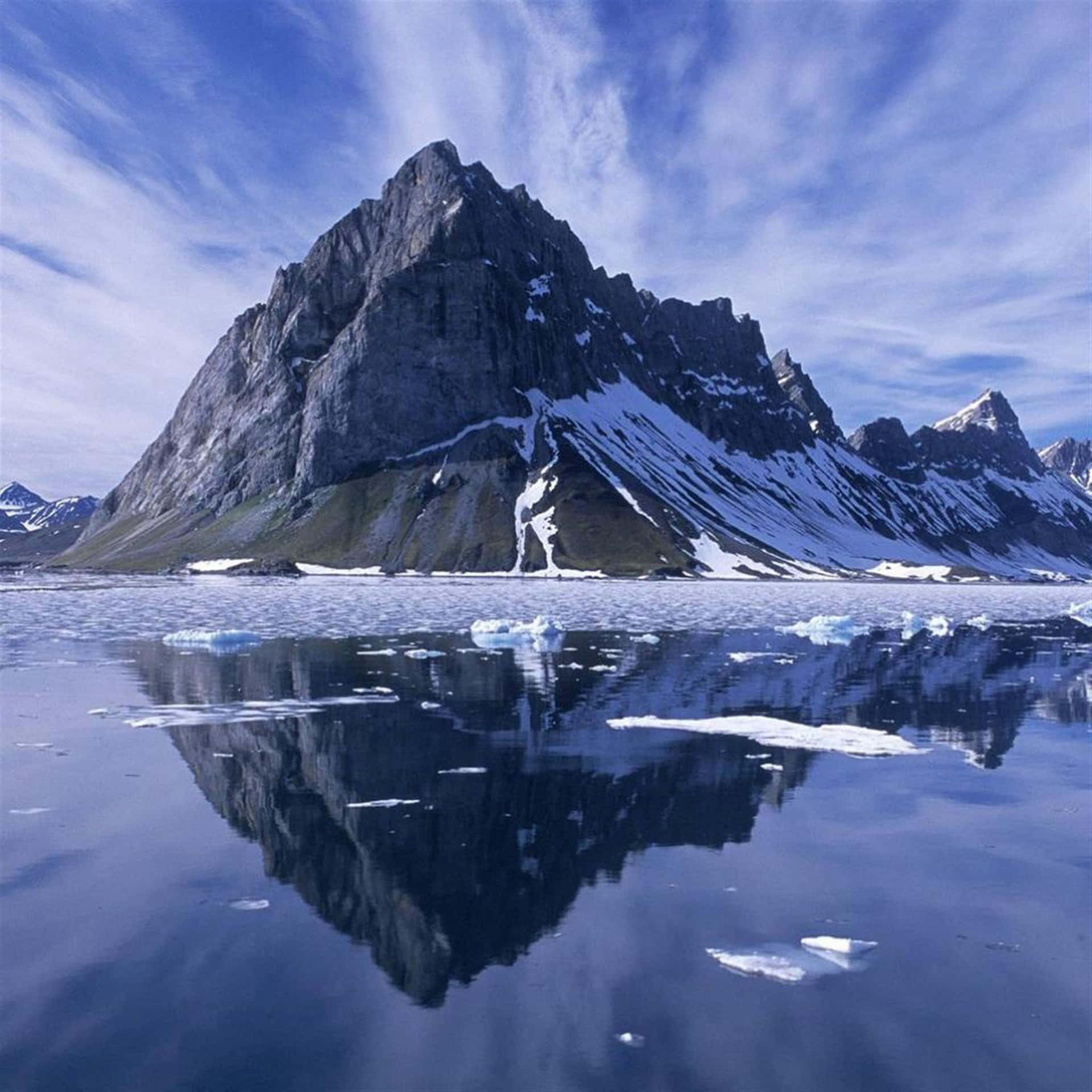 Iceland 桌布 壁紙 — 在帶有條紋的藍天下，一座鋸齒狀、積雪的山峰完美地倒映在玻璃般的冰湖中。