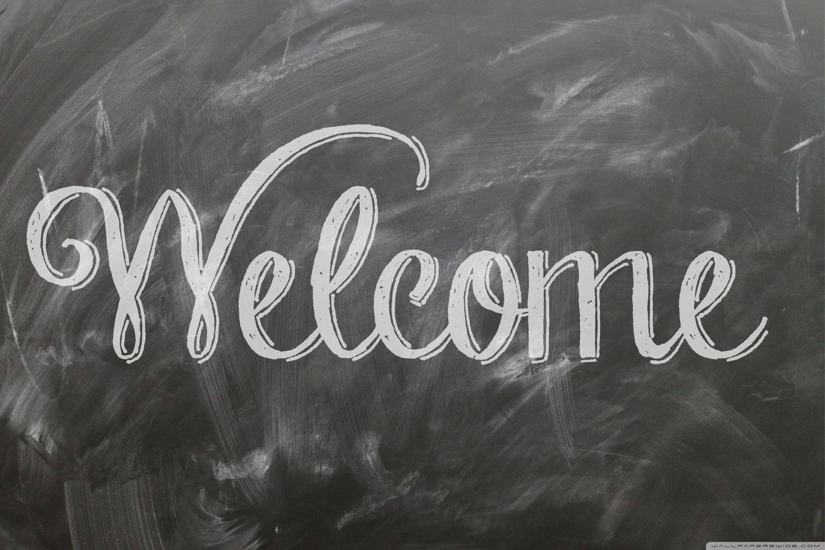 Welcome 桌布 壁紙 — 在帶有紋理的深灰色黑板表面上，用優雅的白色草書寫著「Welcome」。