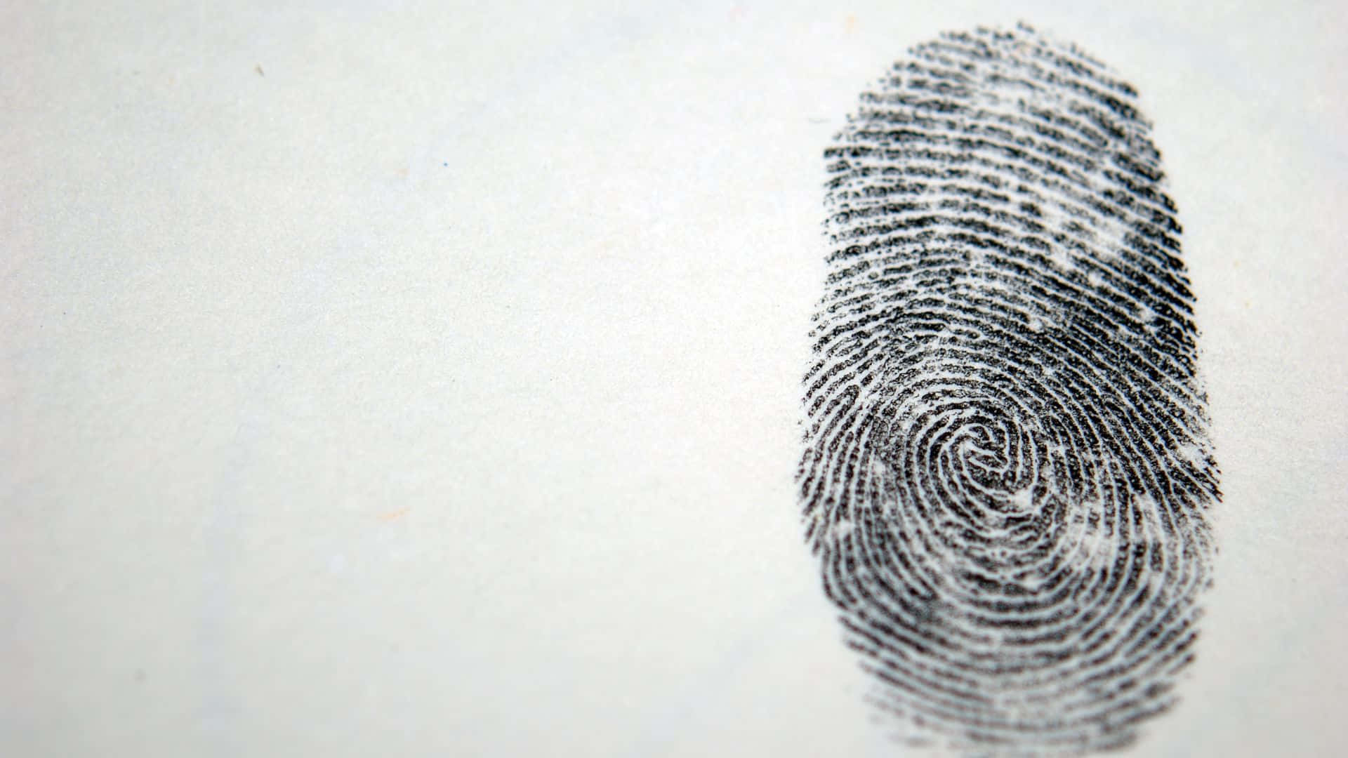 Fingerprint 桌布 壁紙 — 在帶有紋理的米白色紙張上，有一個細節清晰的黑色指紋污跡，並留有充足的留白空間。