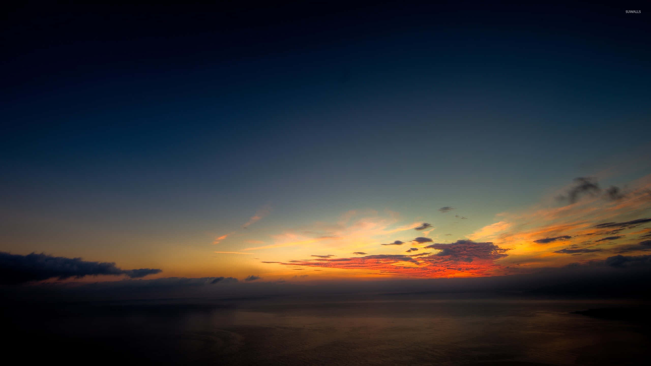 夕陽天空 桌布 壁紙 — 在平靜的海洋上，壯麗的日落，火紅的橙色和紅色雲彩映襯著深藍色的暮色天空。