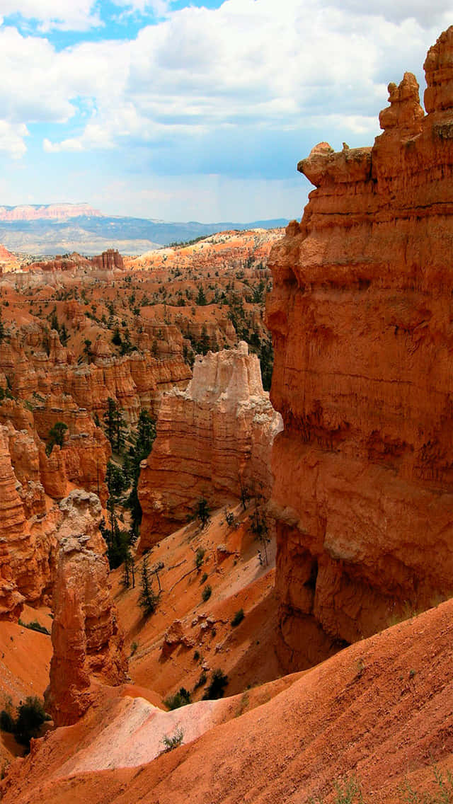 National Parks 桌布 壁紙 — 在廣闊的峽谷景觀中，部分多雲的藍天下，橙色岩柱和紅色岩層的壯麗景色。