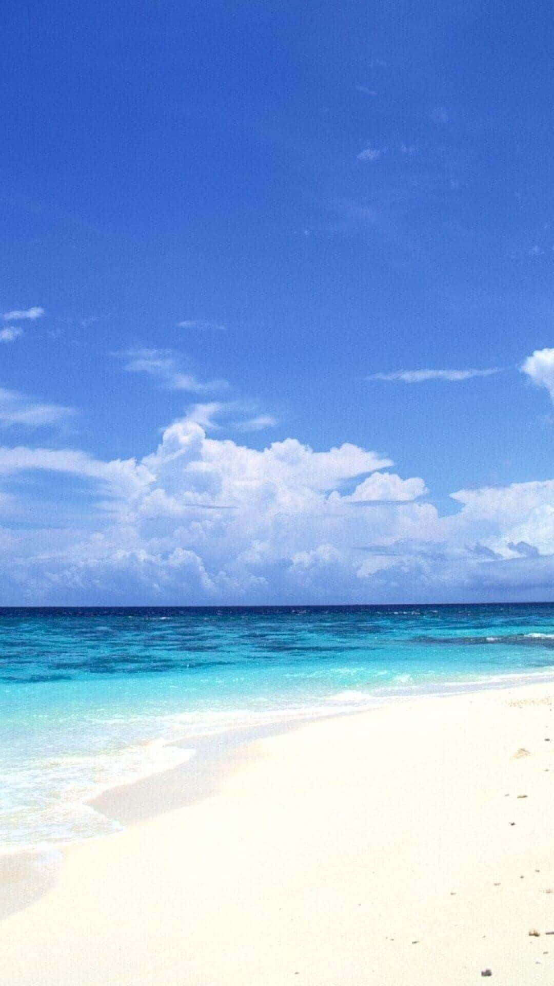 桌布 壁紙 — 在廣闊的藍天和蓬鬆的白雲下，純淨的白色沙灘與碧綠的海浪相遇。