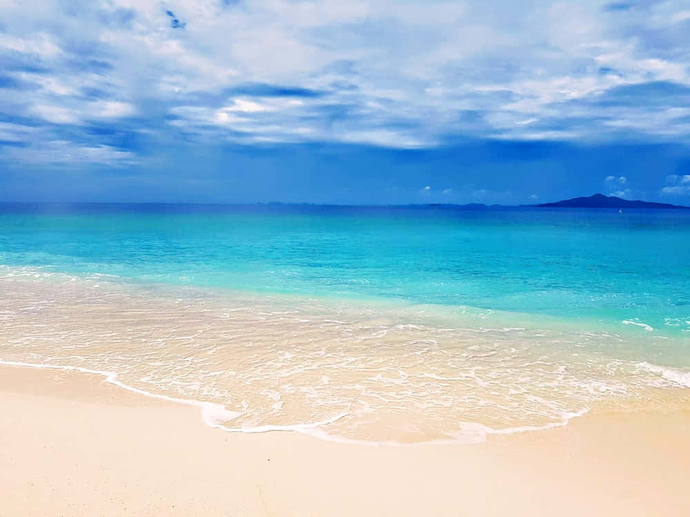 海洋 桌布 壁紙 — 在廣闊的藍天白雲下，碧綠的海浪輕輕拍打著純淨的白色沙灘。