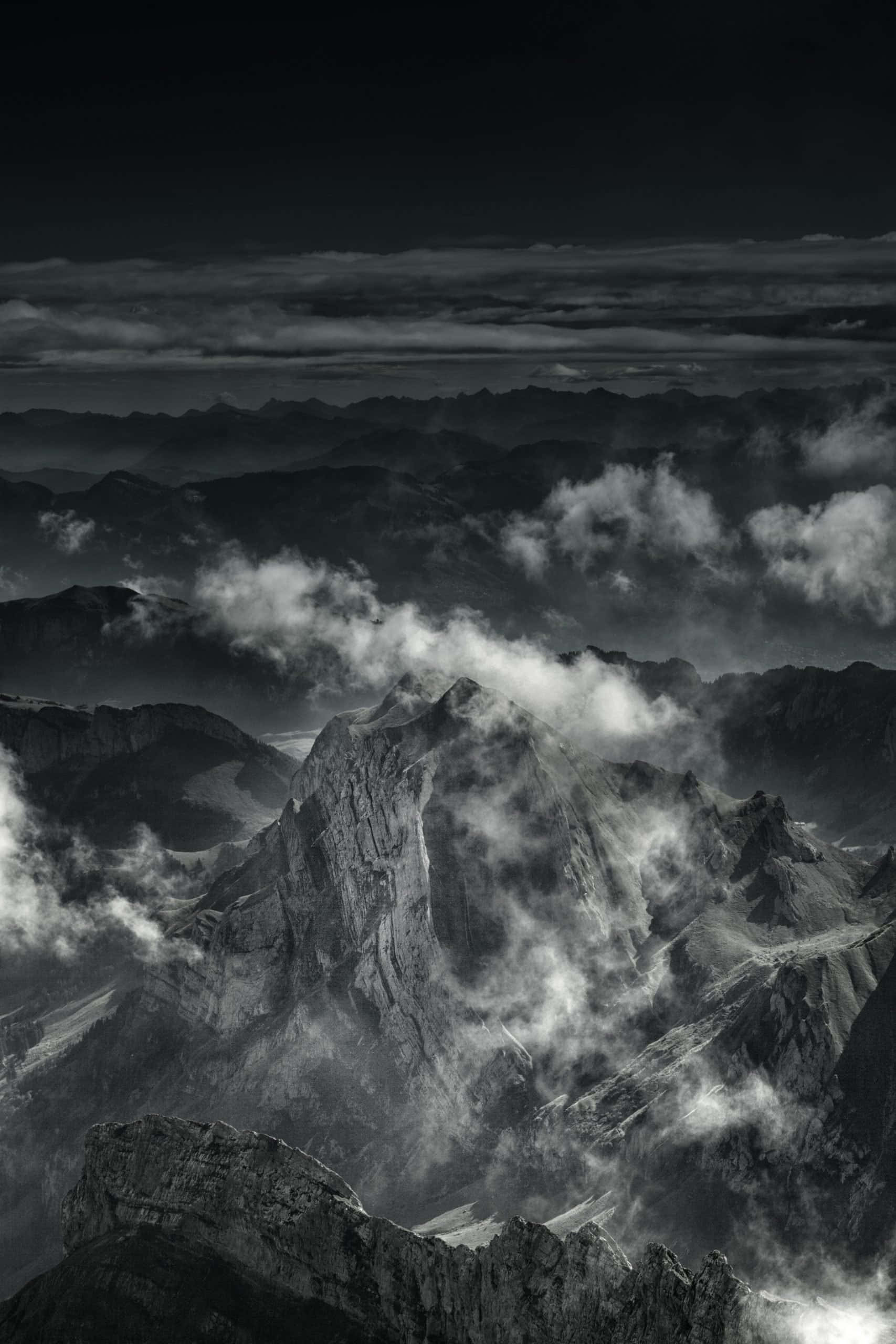 Black And White Storm 桌布 壁紙 — 在廣闊的高地景觀中，一個戲劇性的黑白山峰穿過旋轉的雲層升起。