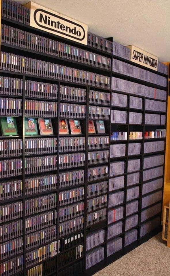 Game Console Emulators 桌布 壁紙 — 在復古遊戲室中，一面高聳的黑架子牆，塞滿了任天堂和超級任天堂的遊戲卡帶。