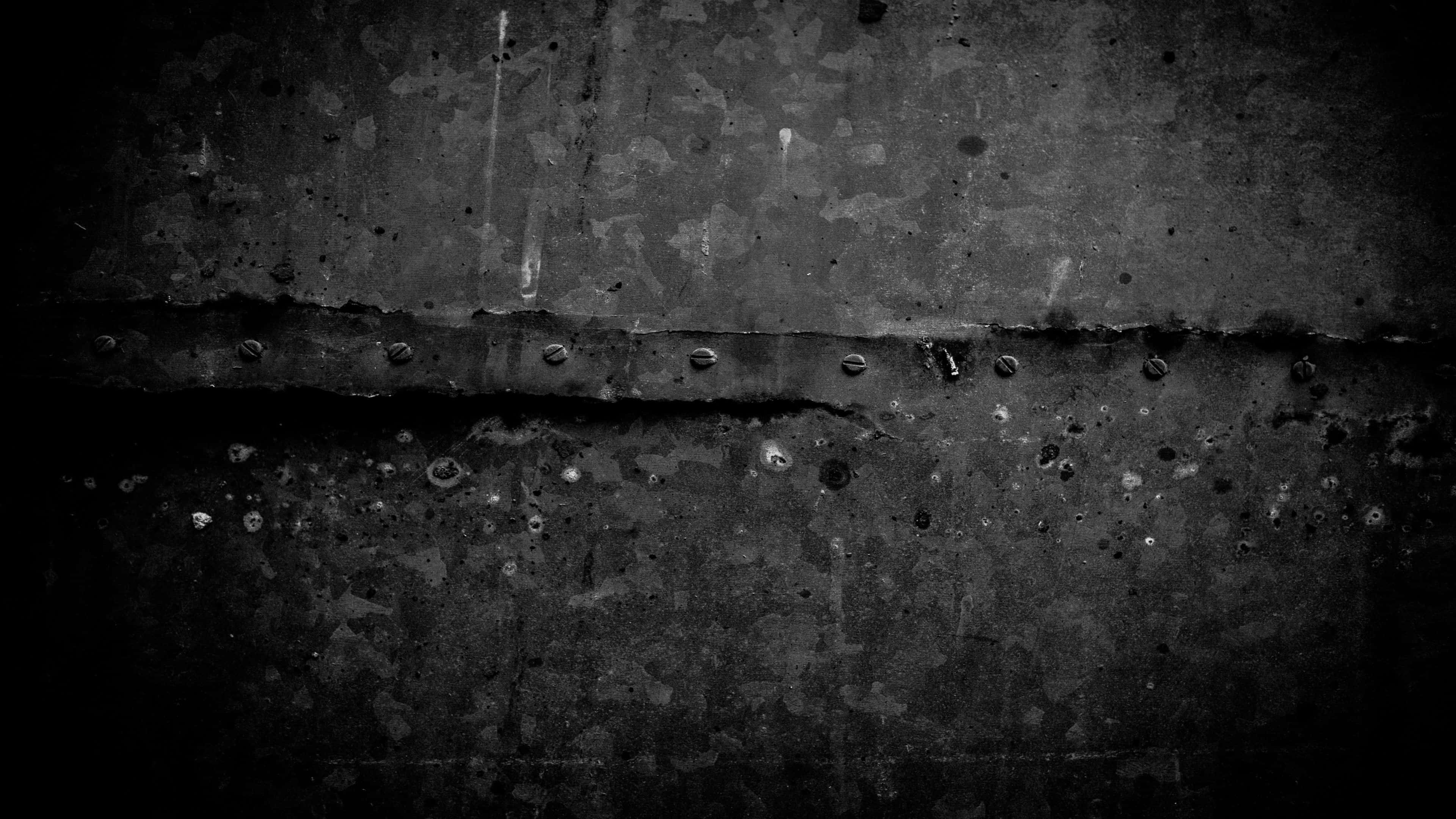 Aesthetic Black Grunge 桌布 壁紙 — 在戲劇性燈光下，帶有鉚釘和鏽跡的風化金屬的粗糙黑白特寫。