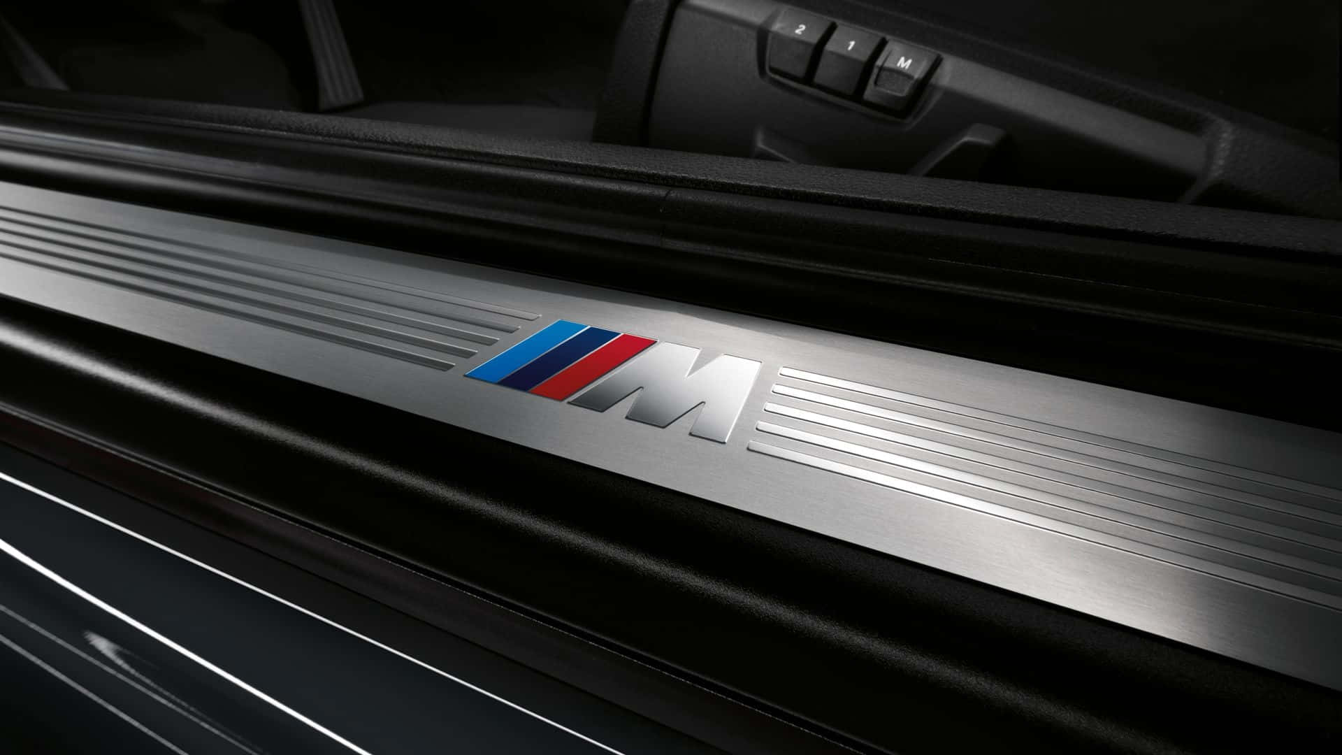 BMW 動圖 桌布 壁紙 — 在戲劇性燈光下，時尚銀色BMW M門檻飾板特寫，帶有藍、紅、白條紋。