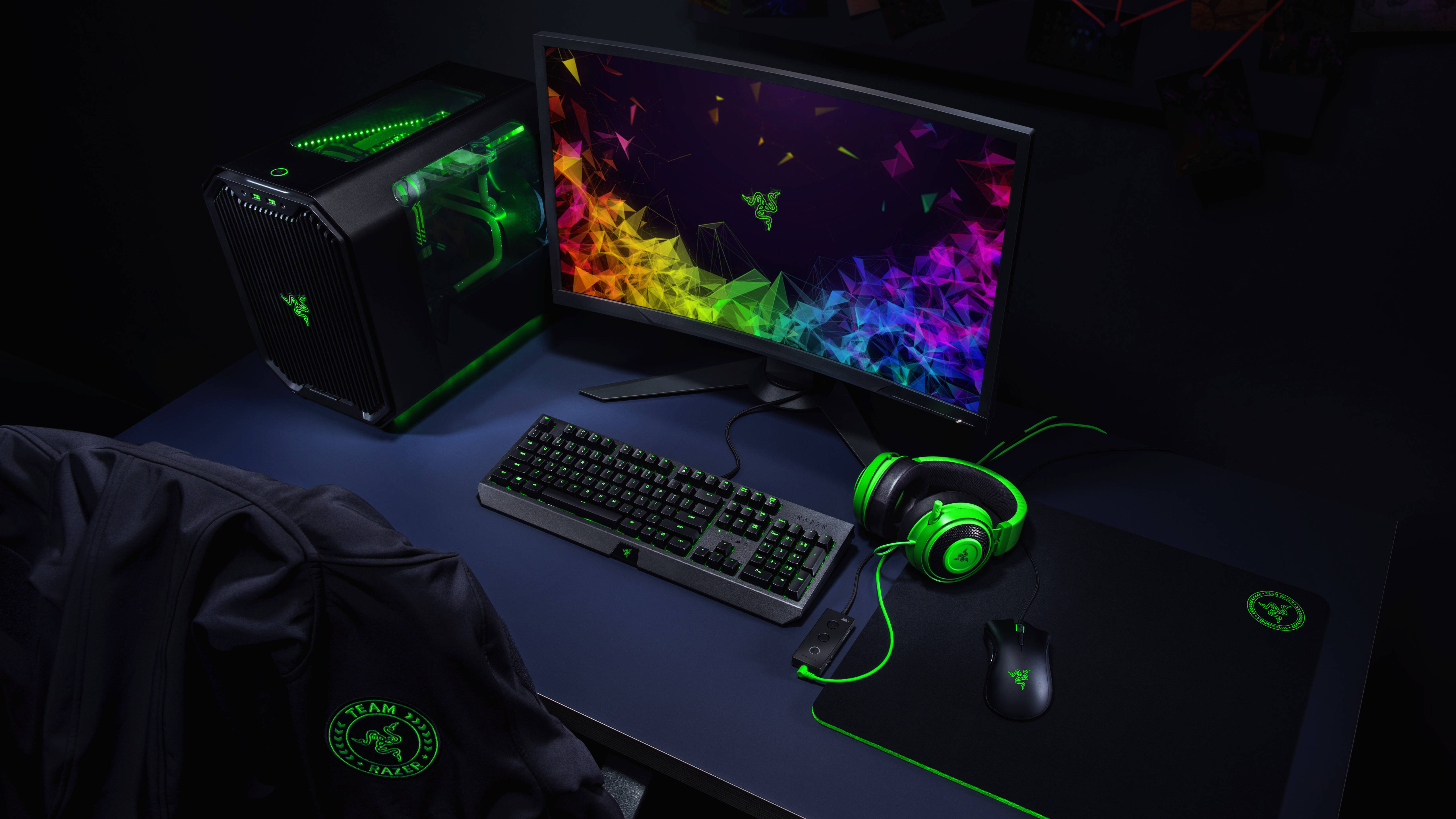 遊戲 桌布 壁紙 — 在戲劇性燈光下，暗色桌子上配備發光綠色 Razer 裝備的時尚遊戲設置。