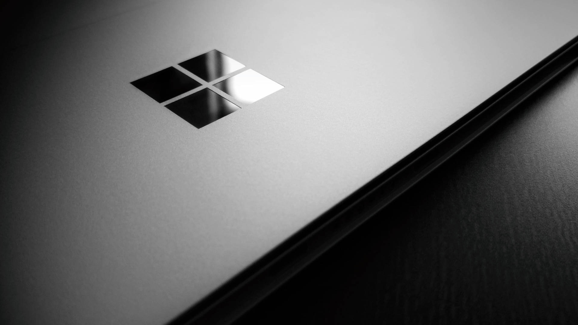 工作室燈光下帶有Microsoft標誌的黑色筆記型電腦特寫 — 4K筆電壁紙 壁紙