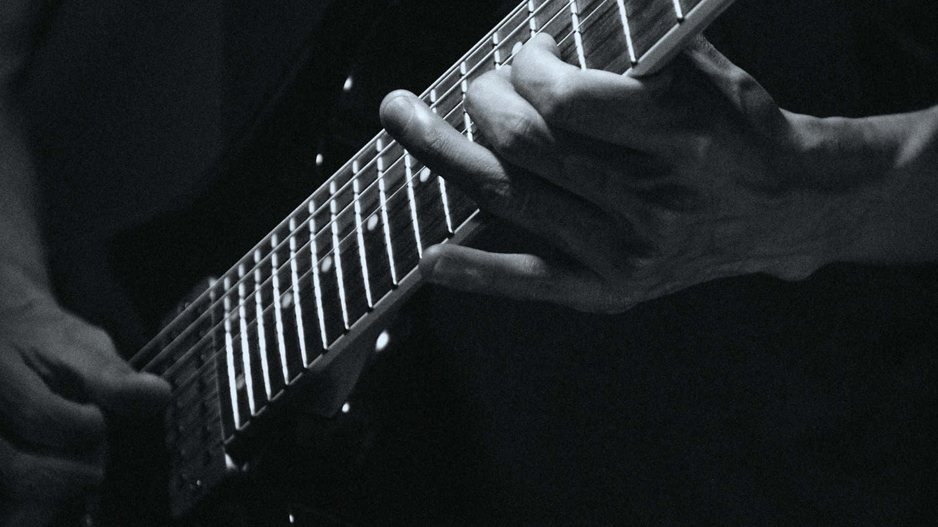Black And White Guitar 桌布 壁紙 — 在戲劇性的舞台燈光下，雙手熟練地彈奏電吉他的黑白特寫。