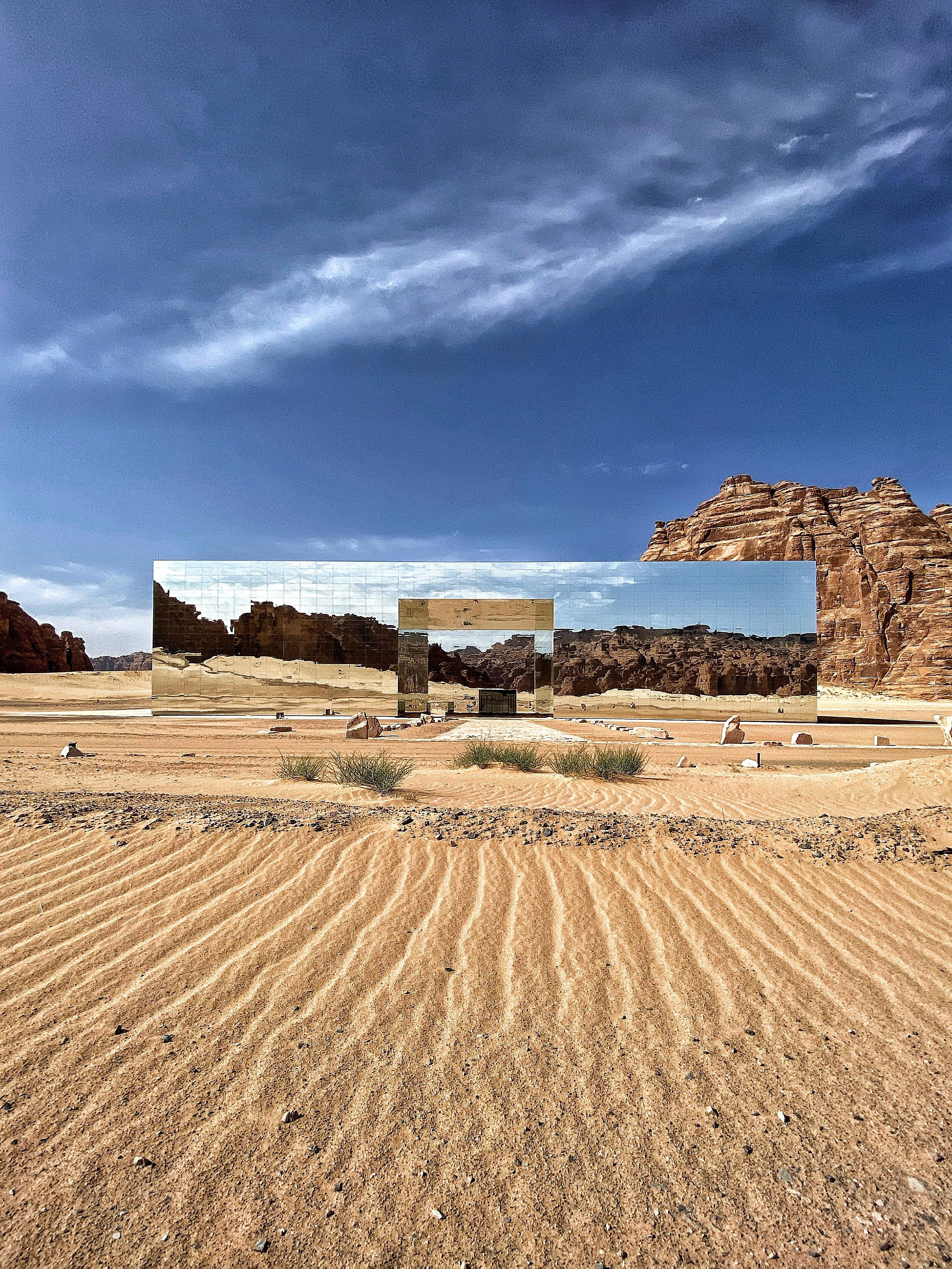 Saudi 桌布 壁紙 — 在戲劇性的藍天白雲下，一個有波紋沙丘和反光鏡面結構的沙漠景觀。