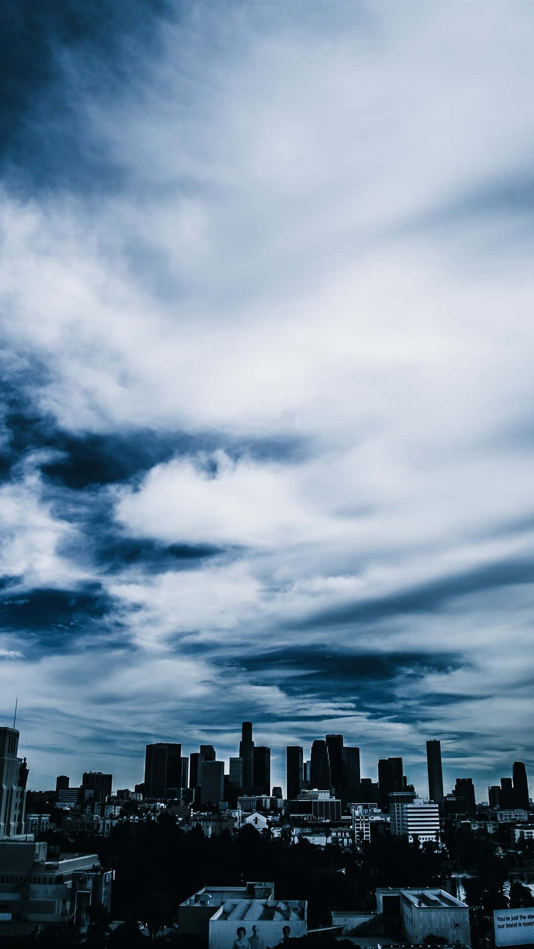 Clouds Aesthetic Tumblr 桌布 壁紙 — 在戲劇性的藍白雲天下，陰暗的摩天大樓構成憂鬱的城市天際線。