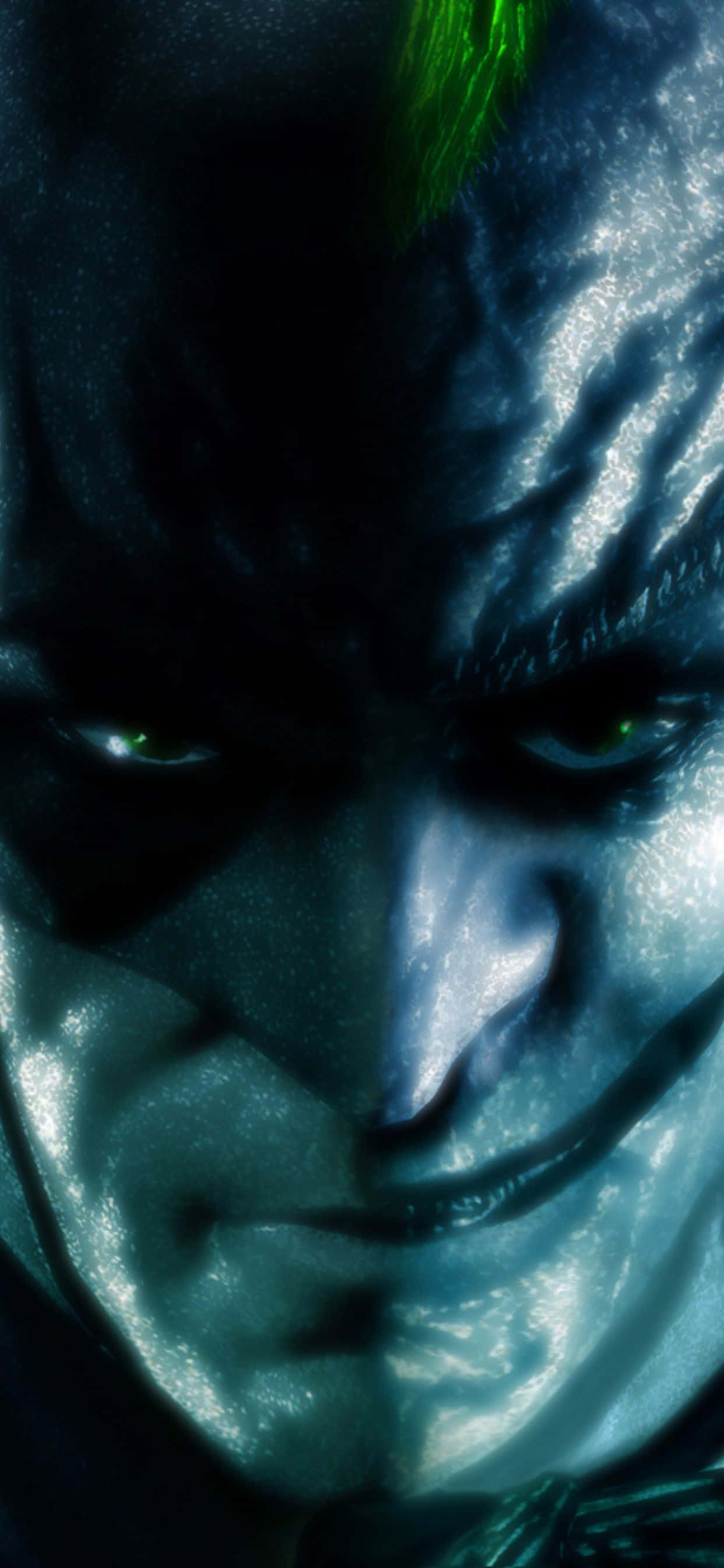 iPhone Xs Max Batman Arkham City 桌布 壁紙 — 在戲劇性的藍色燈光下，小丑帶有發光的綠色眼睛和邪惡笑容的威脅性特寫。