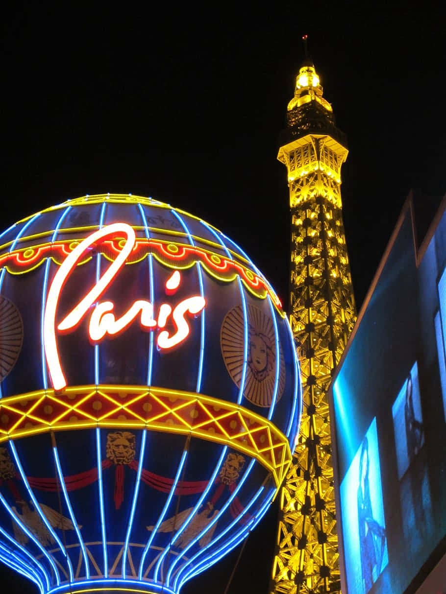 Las Vegas 桌布 壁紙 — 在拉斯維加斯的夜晚，一個耀眼的巴黎熱氣球霓虹燈牌在複製的艾菲爾鐵塔旁閃耀。