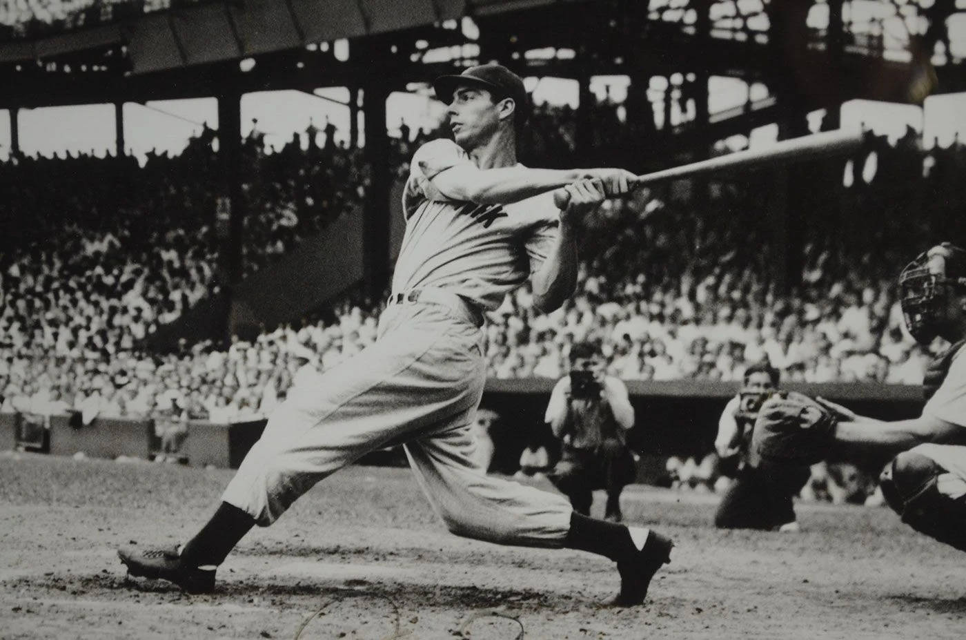 Joe Dimaggio 桌布 壁紙 — 在擠滿觀眾的球場中，一名棒球手揮棒擊球的瞬間，以引人注目的黑白風格捕捉。