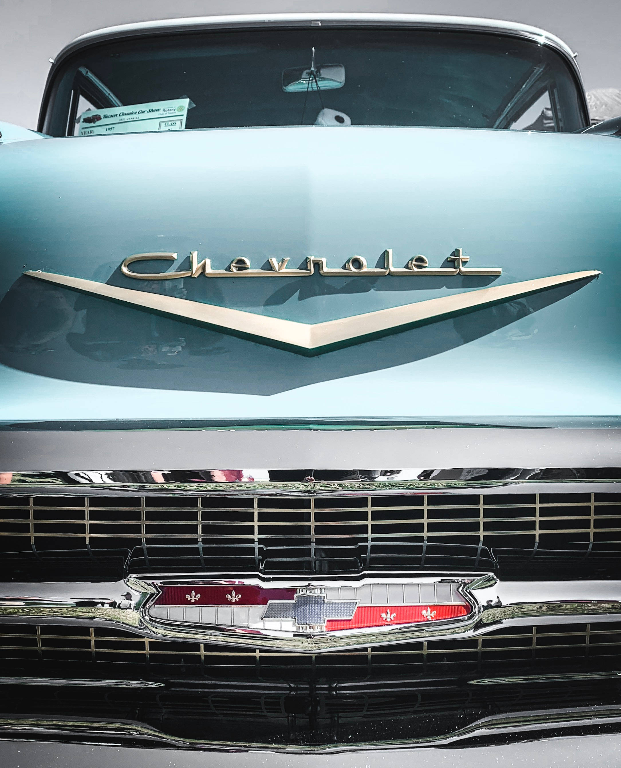 Chevrolet Logo 桌布 壁紙 — 在明亮日光下，一輛復古淺藍色雪佛蘭汽車的前格柵和引擎蓋標誌的特寫。