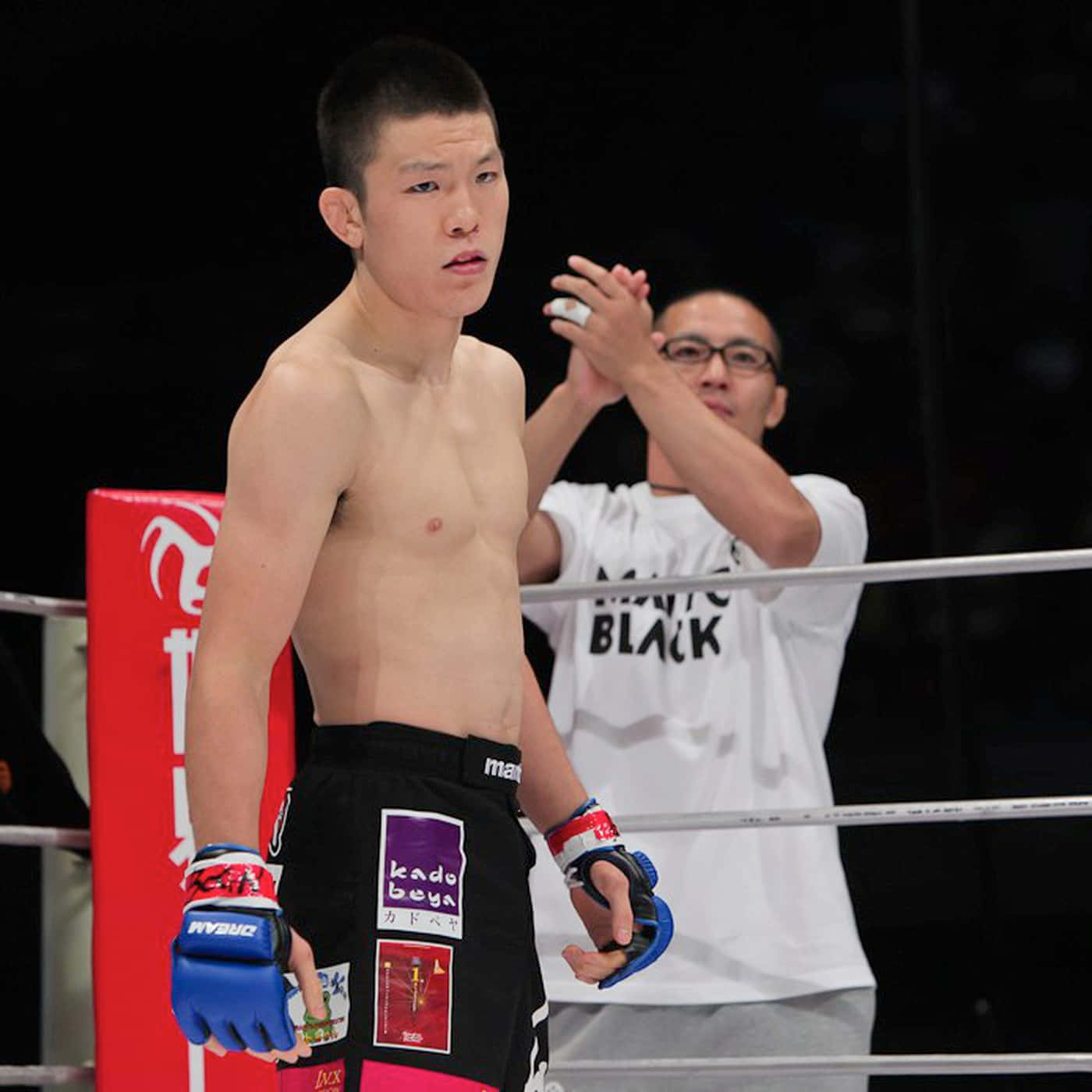 martial arts 桌布 壁紙 — 在明亮的場館燈光下，一位專注的拳擊手在拳擊場上，教練在他身後塗抹藥膏。