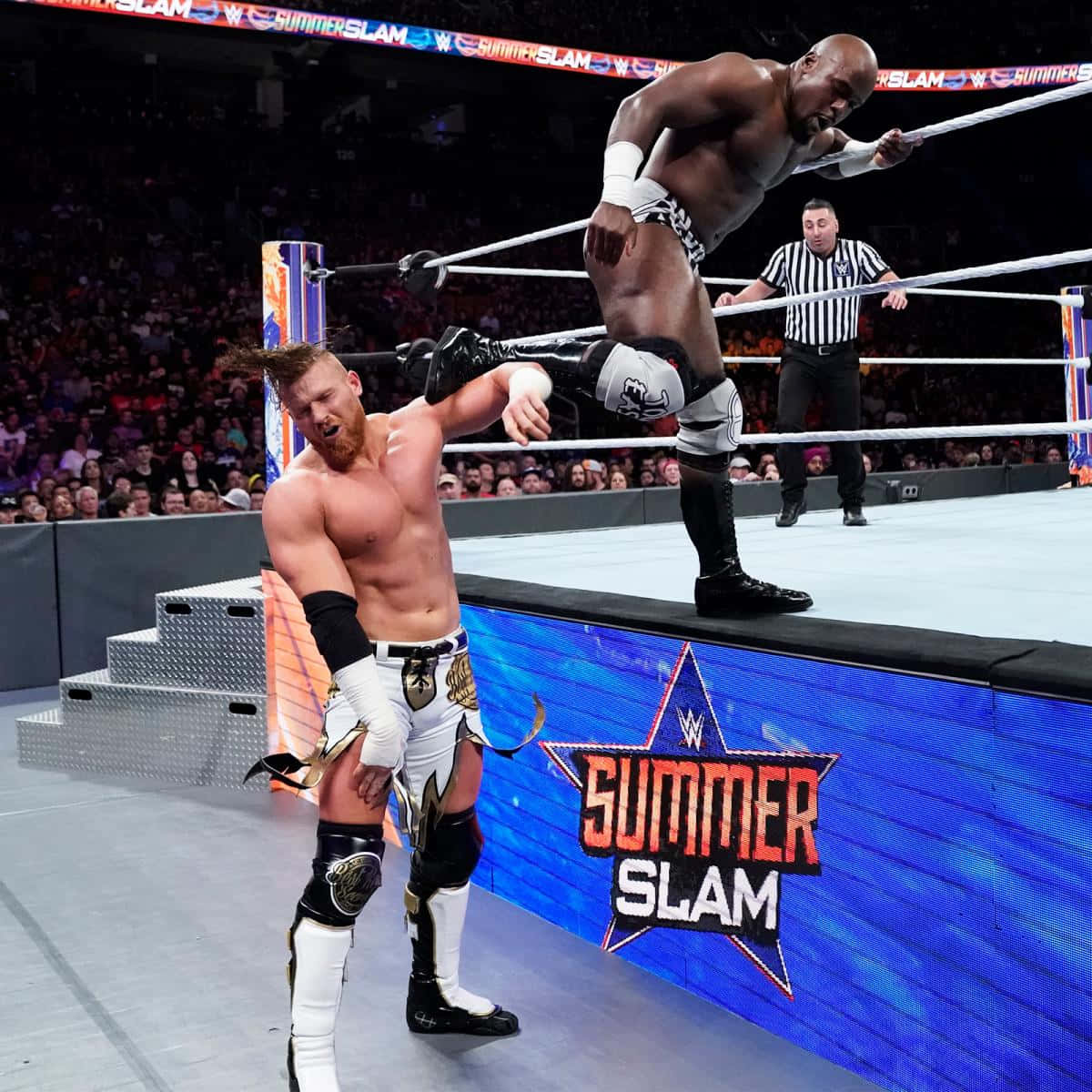 WWE 桌布 壁紙 — 在明亮的場館燈光下，一名摔角手從WWE SummerSlam擂台頂繩躍向對手。