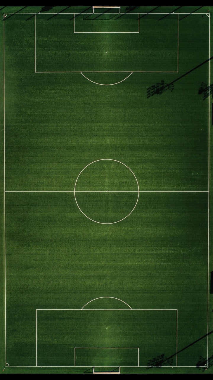 Android Football 桌布 壁紙 — 在明亮的日光下，一個充滿活力的綠色足球場的鳥瞰圖，帶有清晰的白色線條。