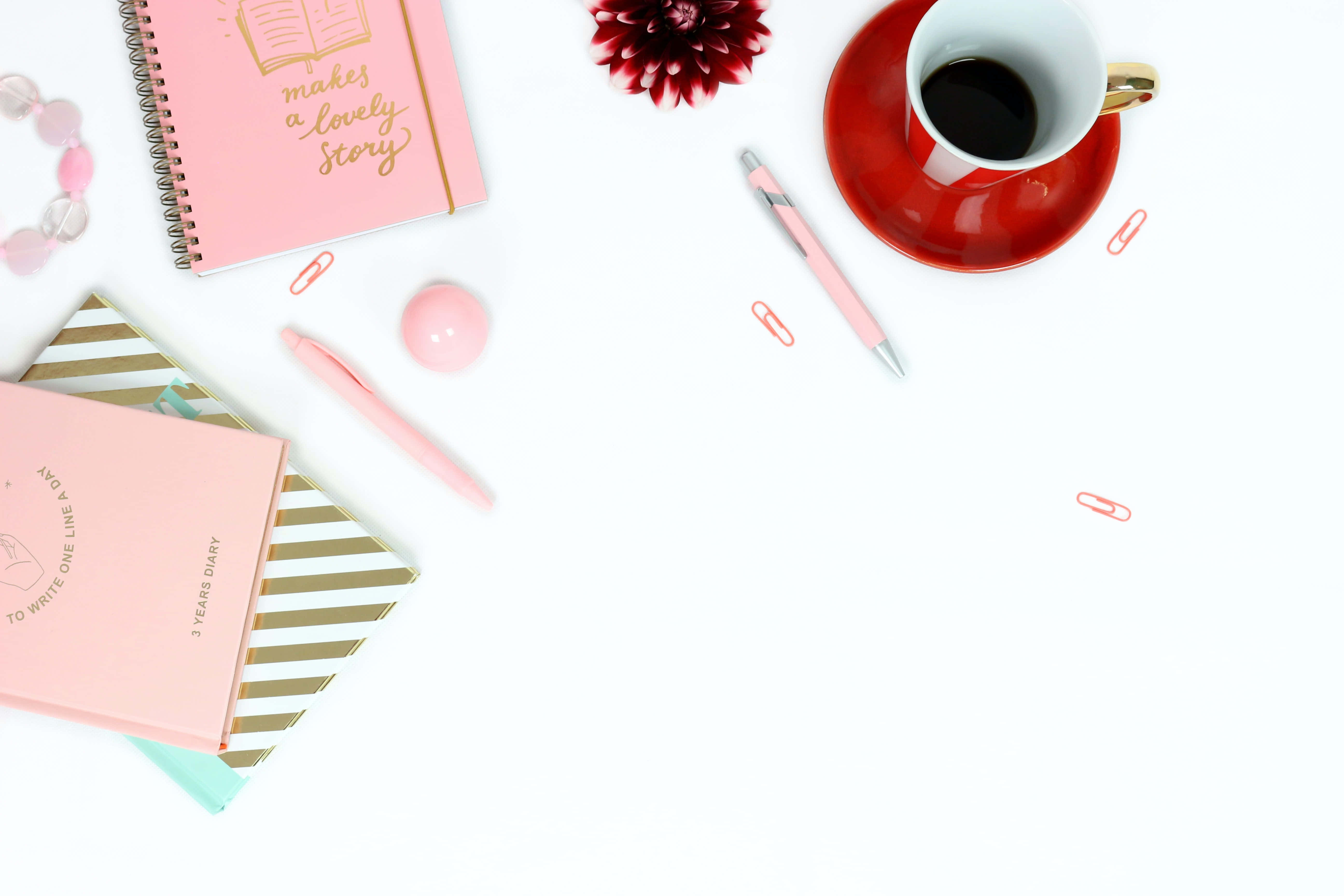 Diary 桌布 壁紙 — 在明亮的白色桌子上，粉紅色文具、咖啡杯和紅色花朵的平鋪擺放。