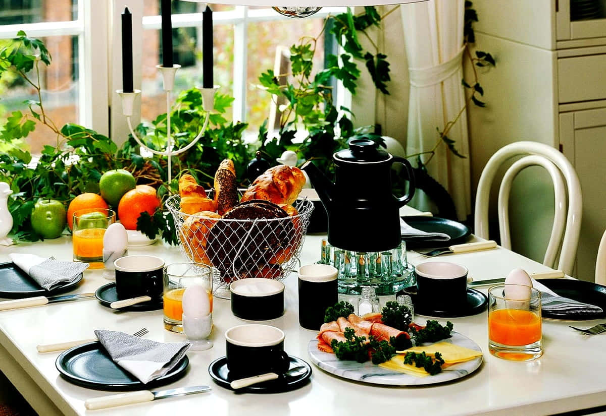 Brunch 桌布 壁紙 — 在明亮的窗邊，一張時尚的早餐桌擺放著黑白餐具、新鮮糕點、柳橙汁和茂盛的綠色植物。