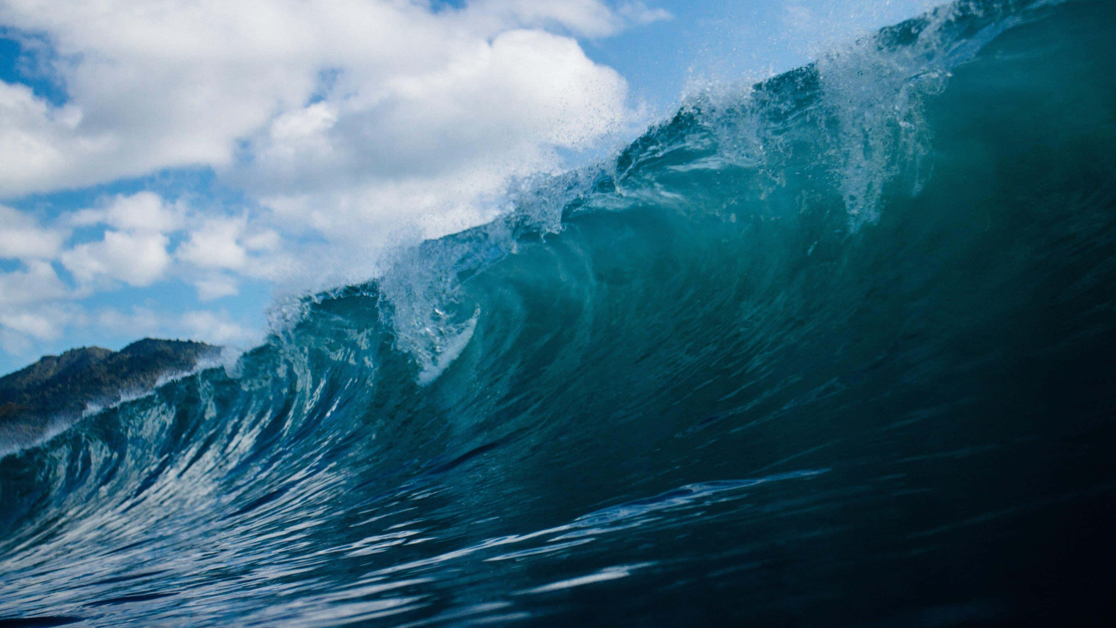 waves 桌布 壁紙 — 在明亮的藍天和蓬鬆的白雲下，巨大的綠松石色海浪強力翻捲。
