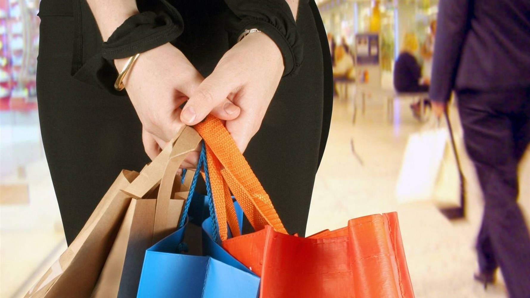 Shopping 桌布 壁紙 — 在明亮的購物中心走廊中，手持色彩繽紛購物袋的特寫。