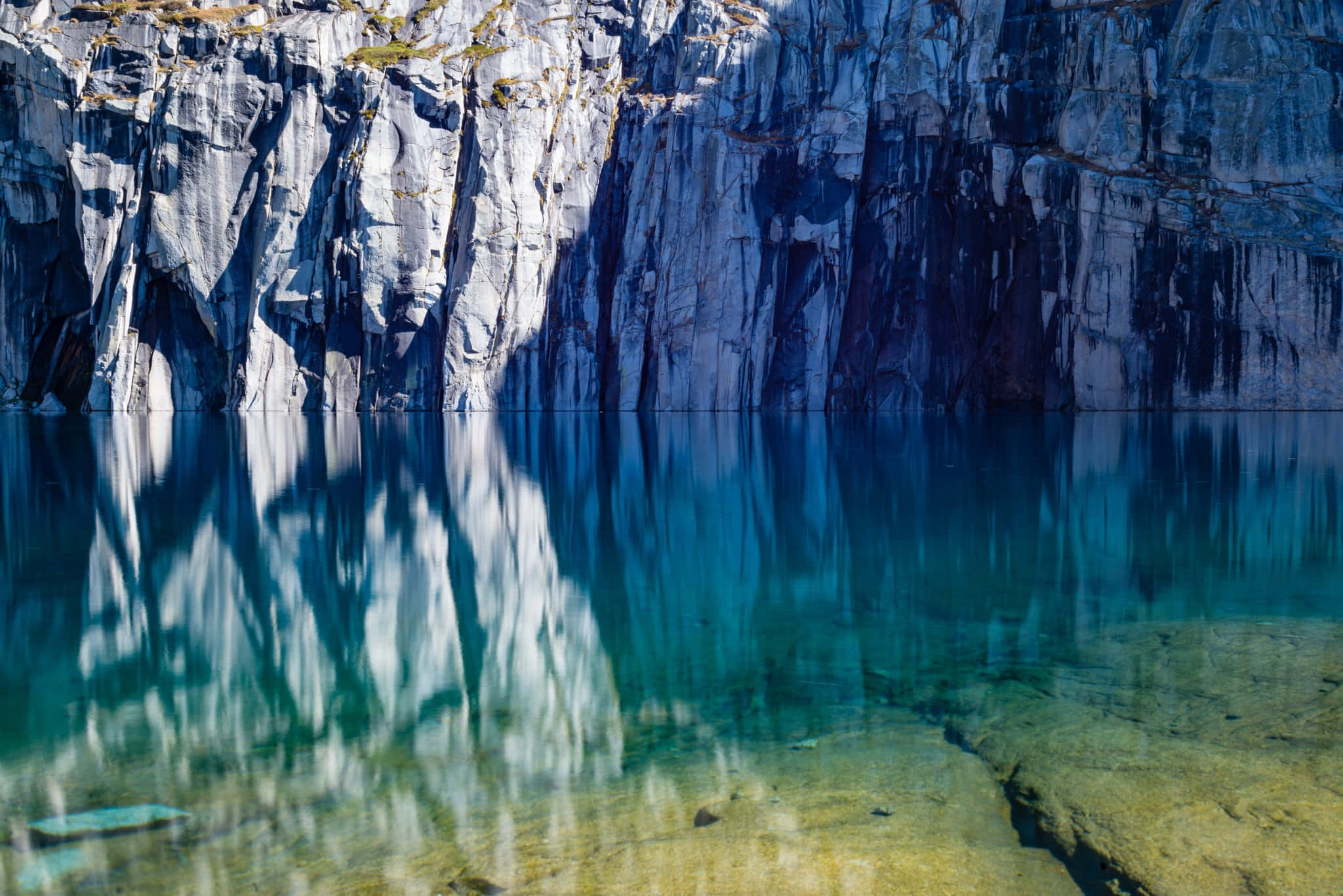 High Sierra 桌布 壁紙 — 在明亮的陽光下，寧靜的湖泊映照著高聳的大理石懸崖，形成令人驚嘆的自然倒影。