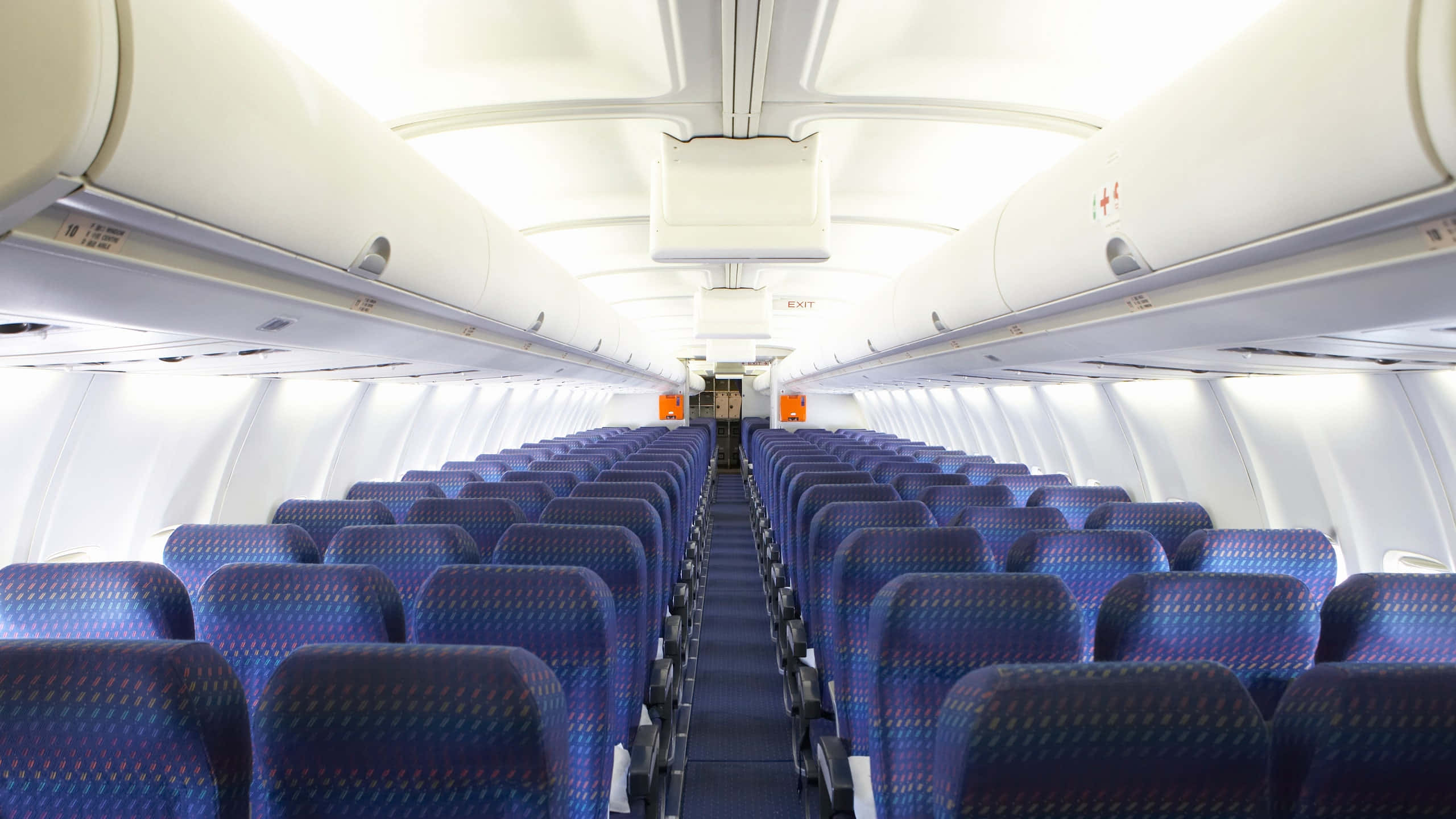 seat 桌布 壁紙 — 在明亮的頂燈下，兩排藍色圖案飛機座椅之間的長長通道。