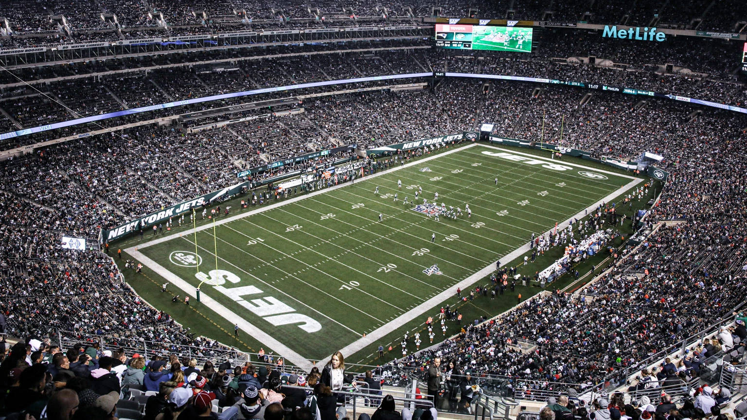 Ny Jets 桌布 壁紙 — 在明亮的體育場燈光下，紐約噴射機隊美式足球比賽期間，滿座的MetLife體育場鳥瞰圖。