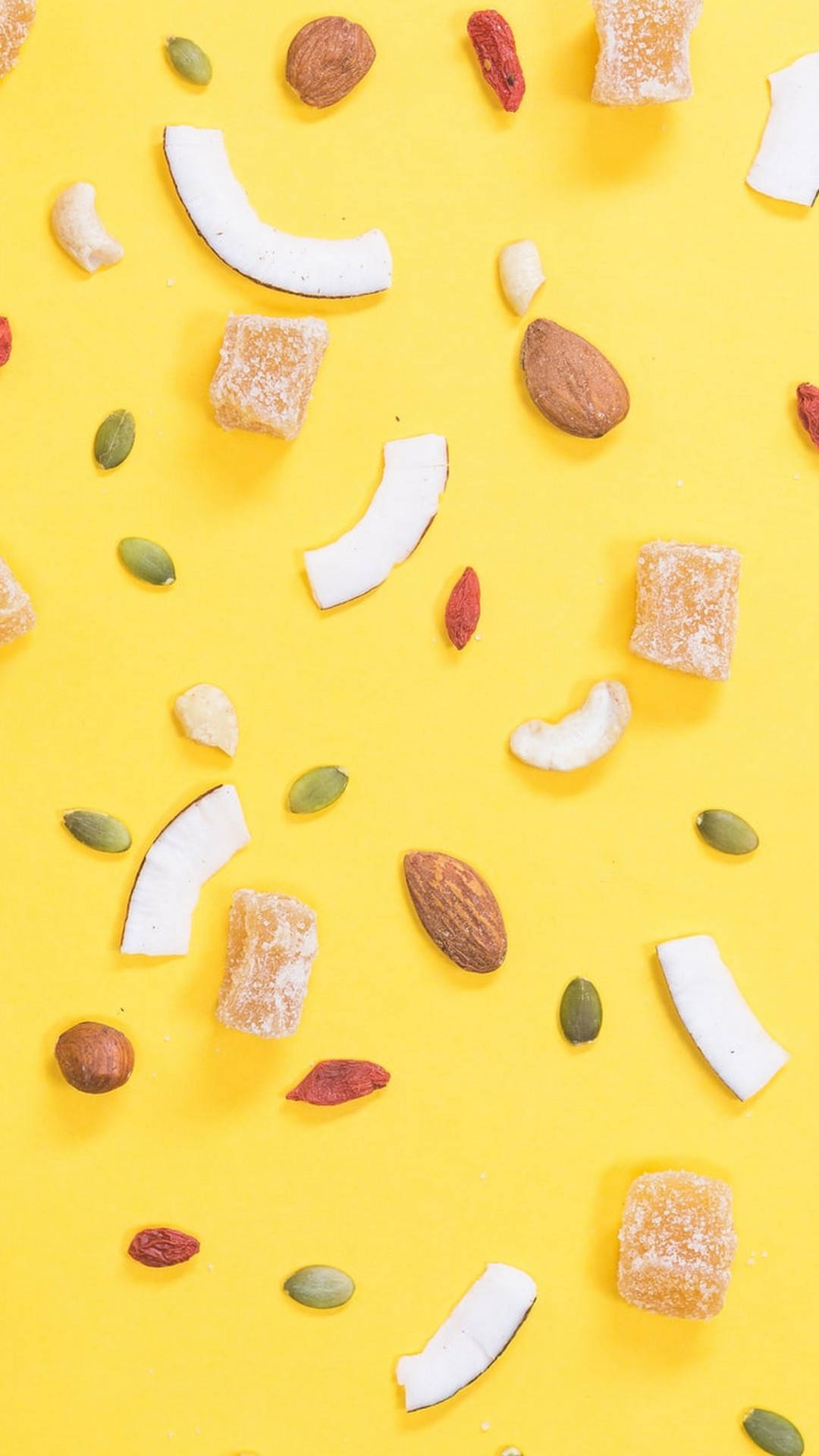 Cute Yellow Aesthetic 桌布 壁紙 — 在明亮的黃色背景上散落著各種乾果和堅果的平鋪佈局。