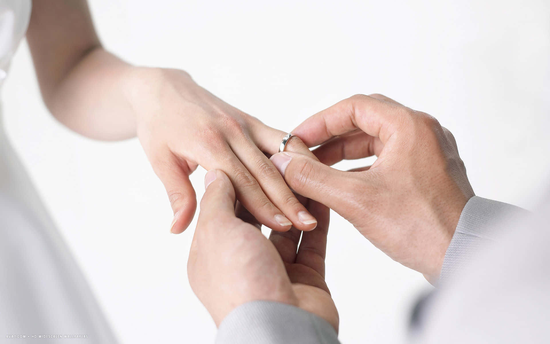 Wedding 桌布 壁紙 — 在明亮簡約的環境中，一名男子輕輕地將銀戒指戴在女子的手指上。