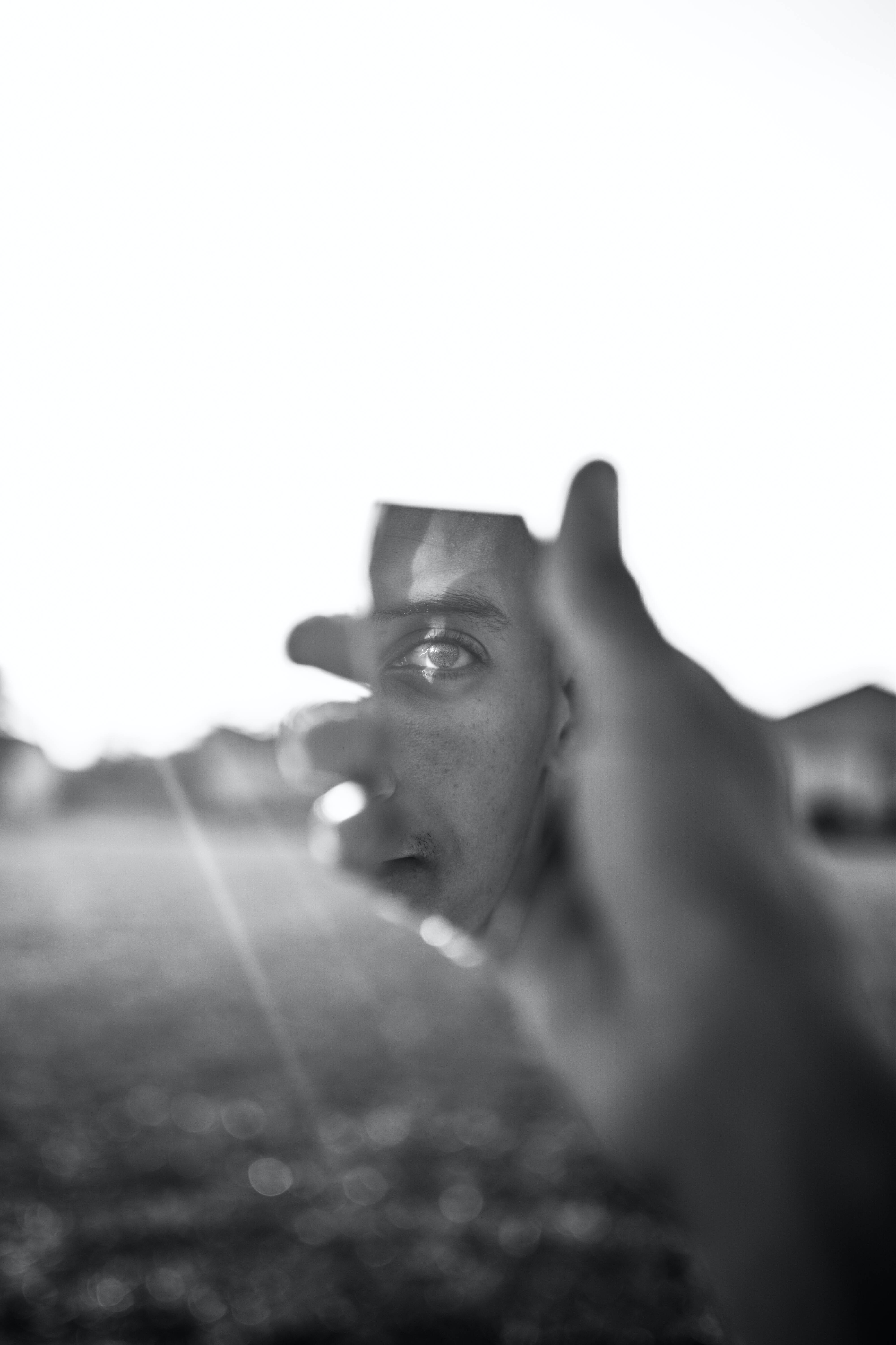 reflection 桌布 壁紙 — 在明亮背景的黑白照片中，一個人的臉被手部分遮擋。