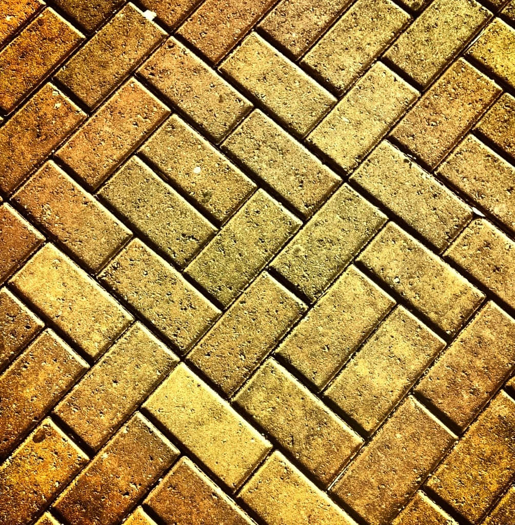 Brick 桌布 壁紙 — 在明亮陽光下，暖色大地色調的人字形圖案鋪路石的近距離特寫。