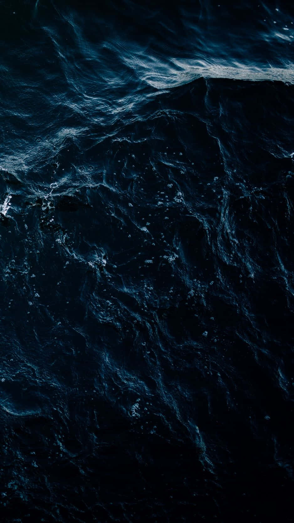 Dark Ocean 桌布 壁紙 — 在昏暗光線下，深藍色海洋波浪翻騰、帶有白色泡沫頂峰的戲劇性航拍視圖。