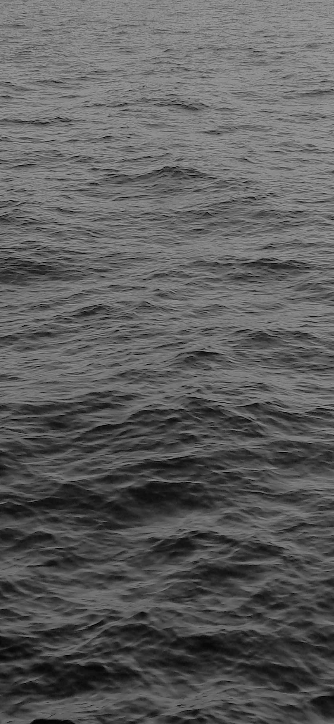 Black And White Ocean 桌布 壁紙 — 在昏暗光線下，紋理化的海浪泛起漣漪的單色特寫。