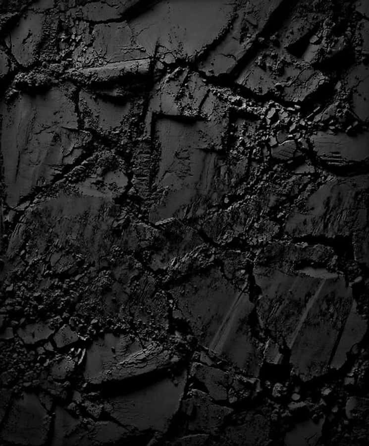 Dark Rock 桌布 壁紙 — 在昏暗燈光下，裂開的黑色瀝青近距離特寫，帶有深色陰影和粗糙質感。