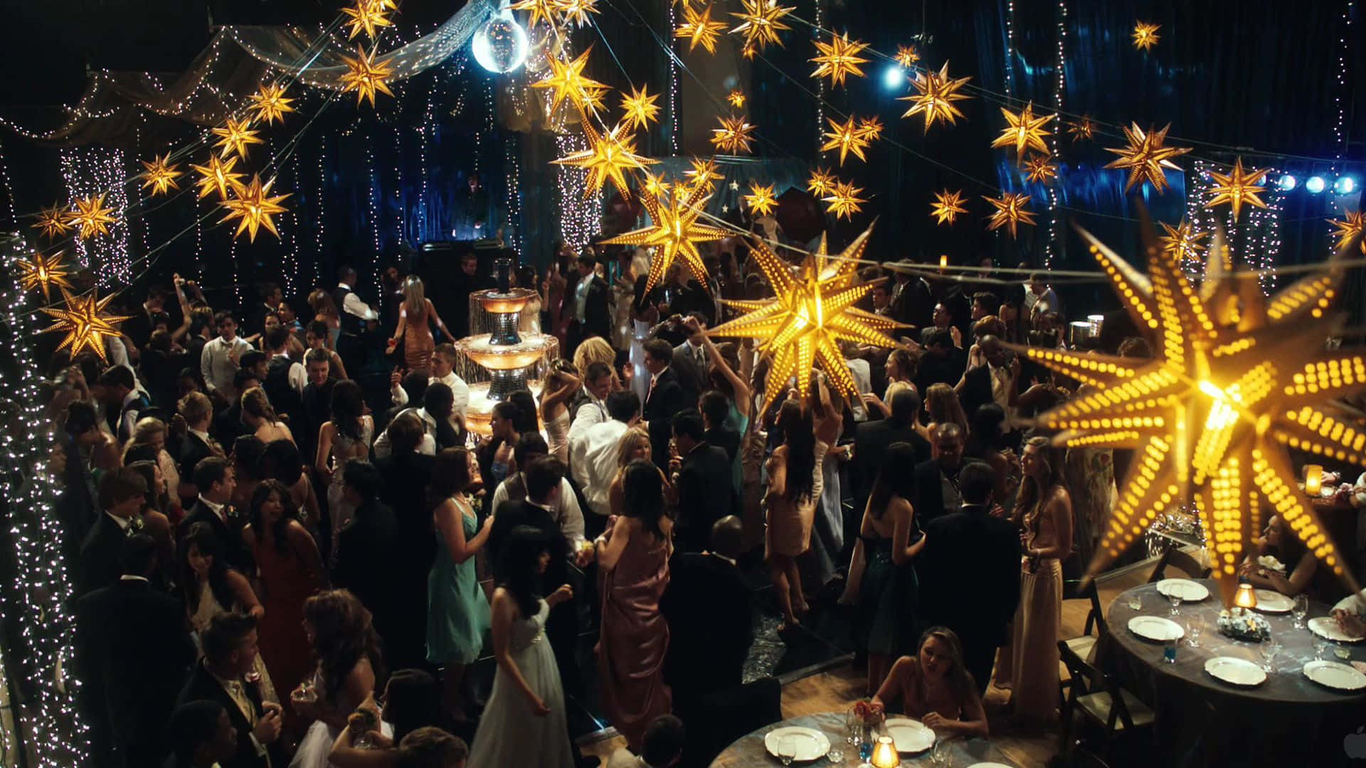 Party 桌布 壁紙 — 在昏暗的舞廳中，閃爍的金色星星裝飾和串燈下，一場擁擠而迷人的派對。