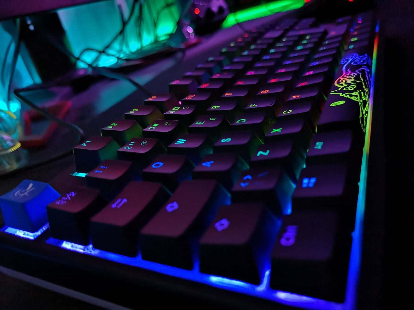 RGB 桌布 壁紙 — 在昏暗設置中，遊戲鍵盤發出鮮豔彩虹背光的特寫。