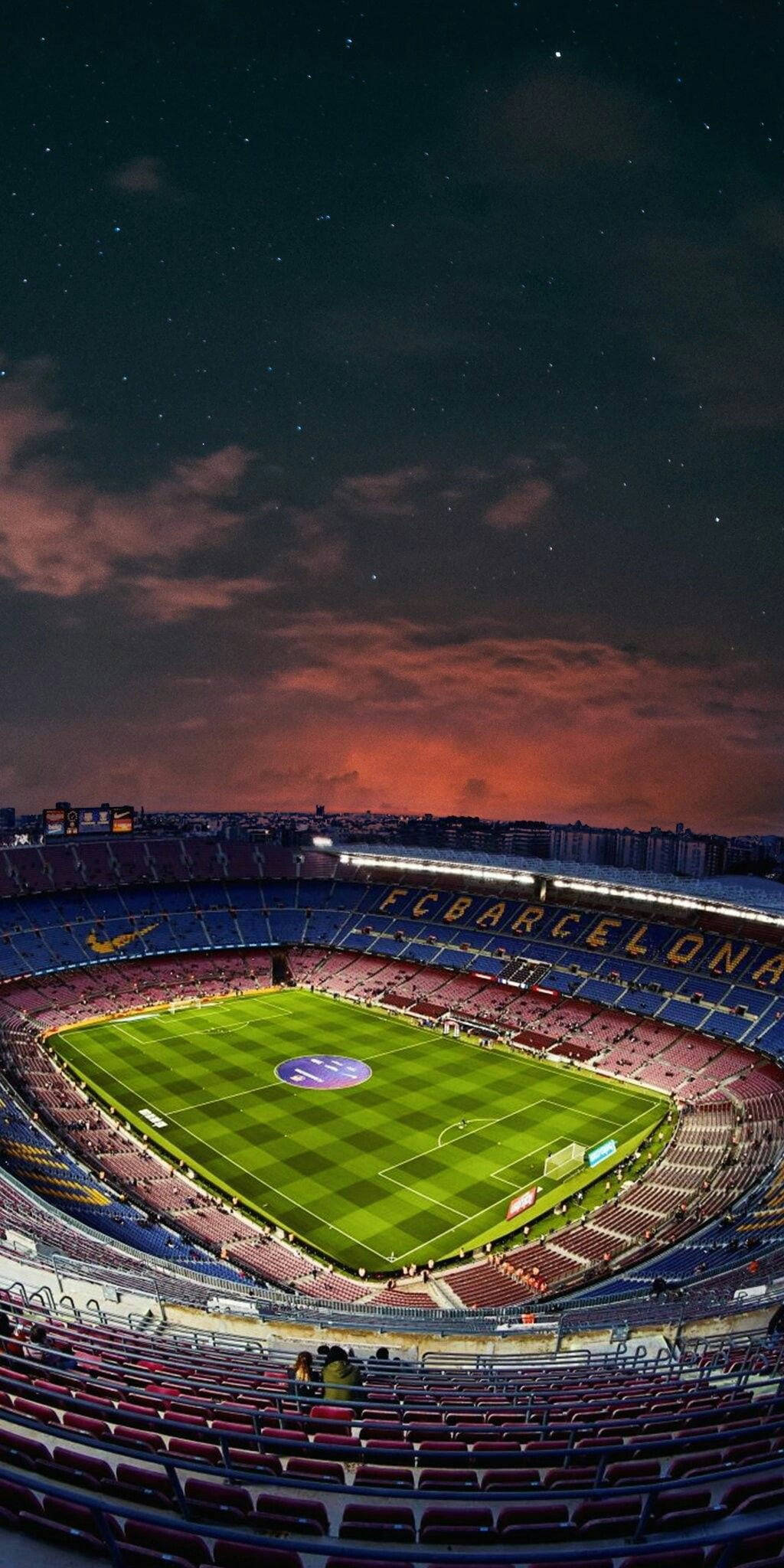 Barcelona 桌布 壁紙 — 在星空下，球場燈光映照著鮮豔橙色雲彩的魯營球場壯麗夜景。