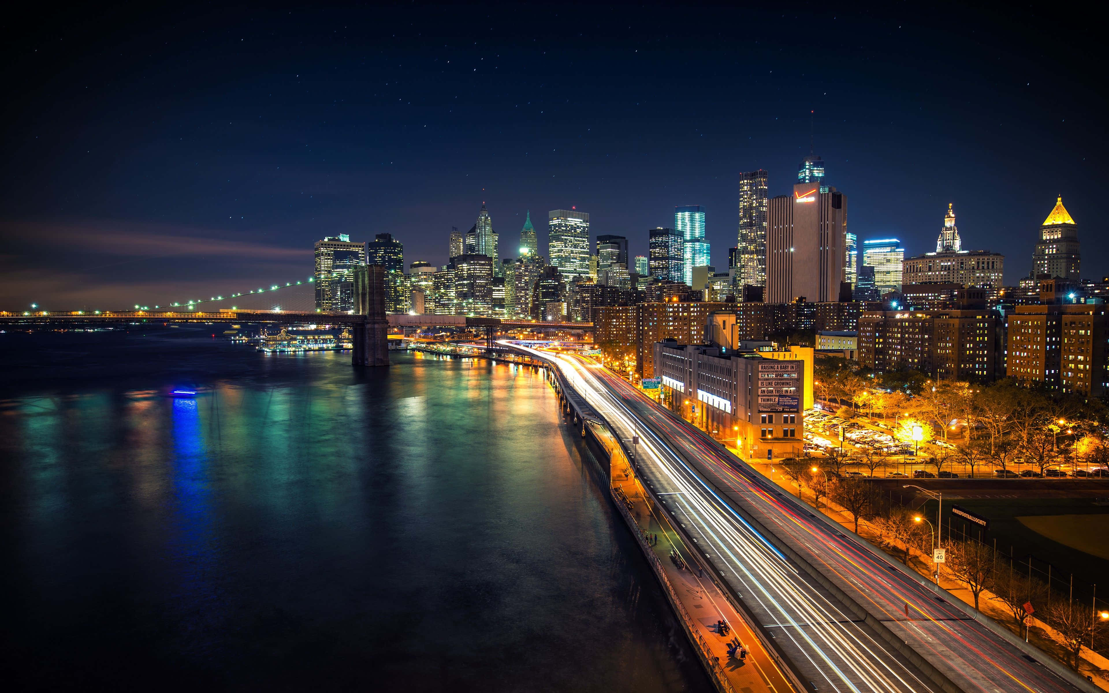 Brooklyn Bridge 桌布 壁紙 — 在星空下，紐約市天際線的耀眼夜景，閃爍的摩天大樓和水上橋樑上交通的光跡。