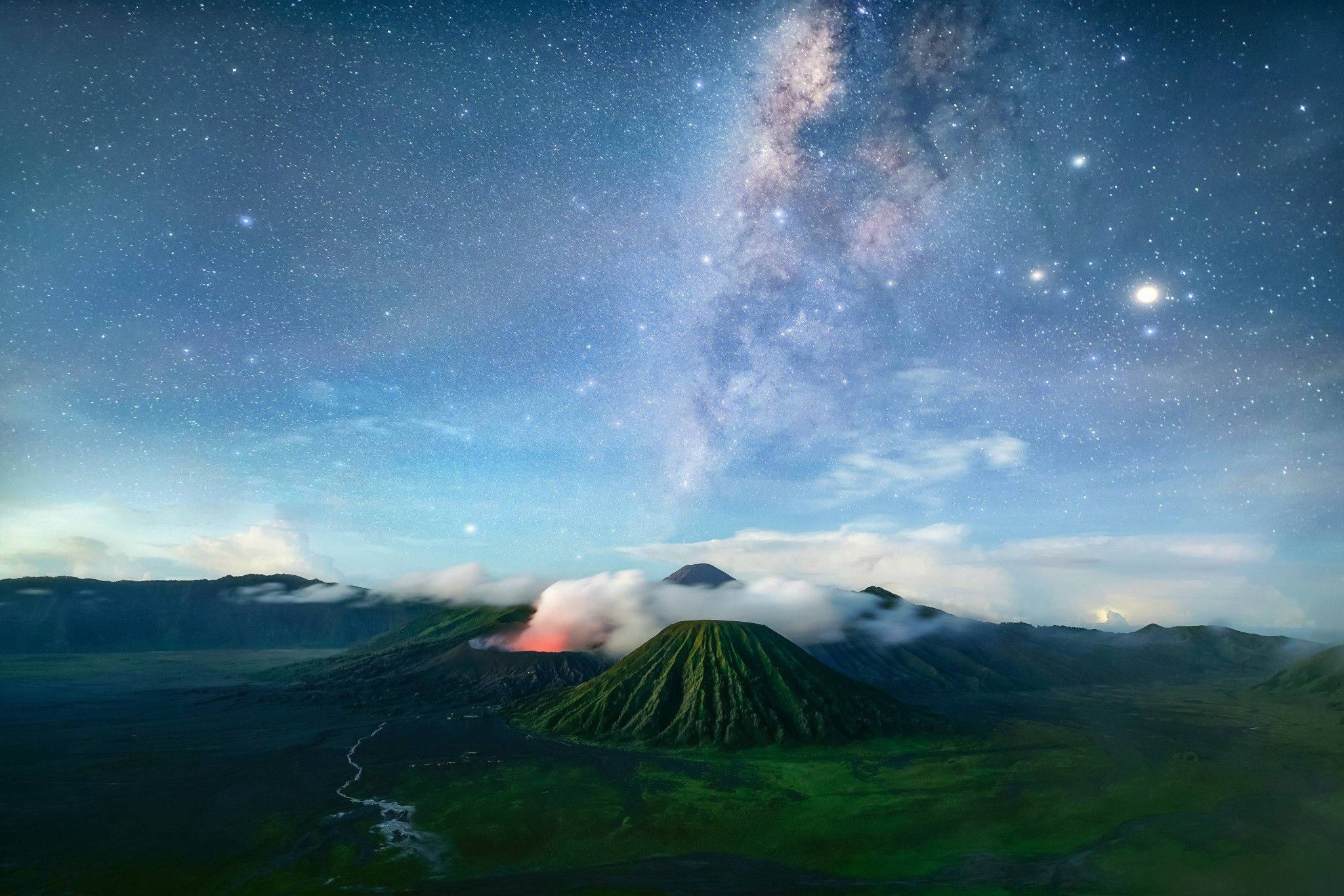 優質 桌布 壁紙 — 在星空下，雄偉的火山景觀，銀河拱起，發光的雲朵飄過綠色山坡。