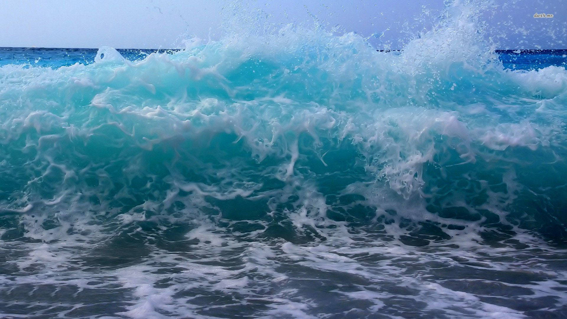 Wave 桌布 壁紙 — 在晴朗的天空下，一道強勁的藍綠色海浪拍打著海岸，激起白色泡沫。