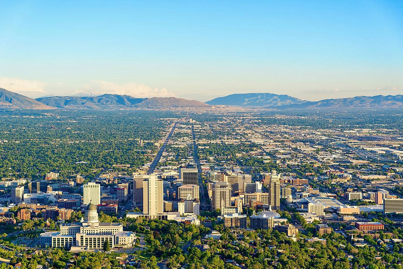 Salt Lake City 桌布 壁紙 — 在晴朗的藍天下，一個廣闊城市的航拍圖，有一條中央大道通向遠處的山脈。