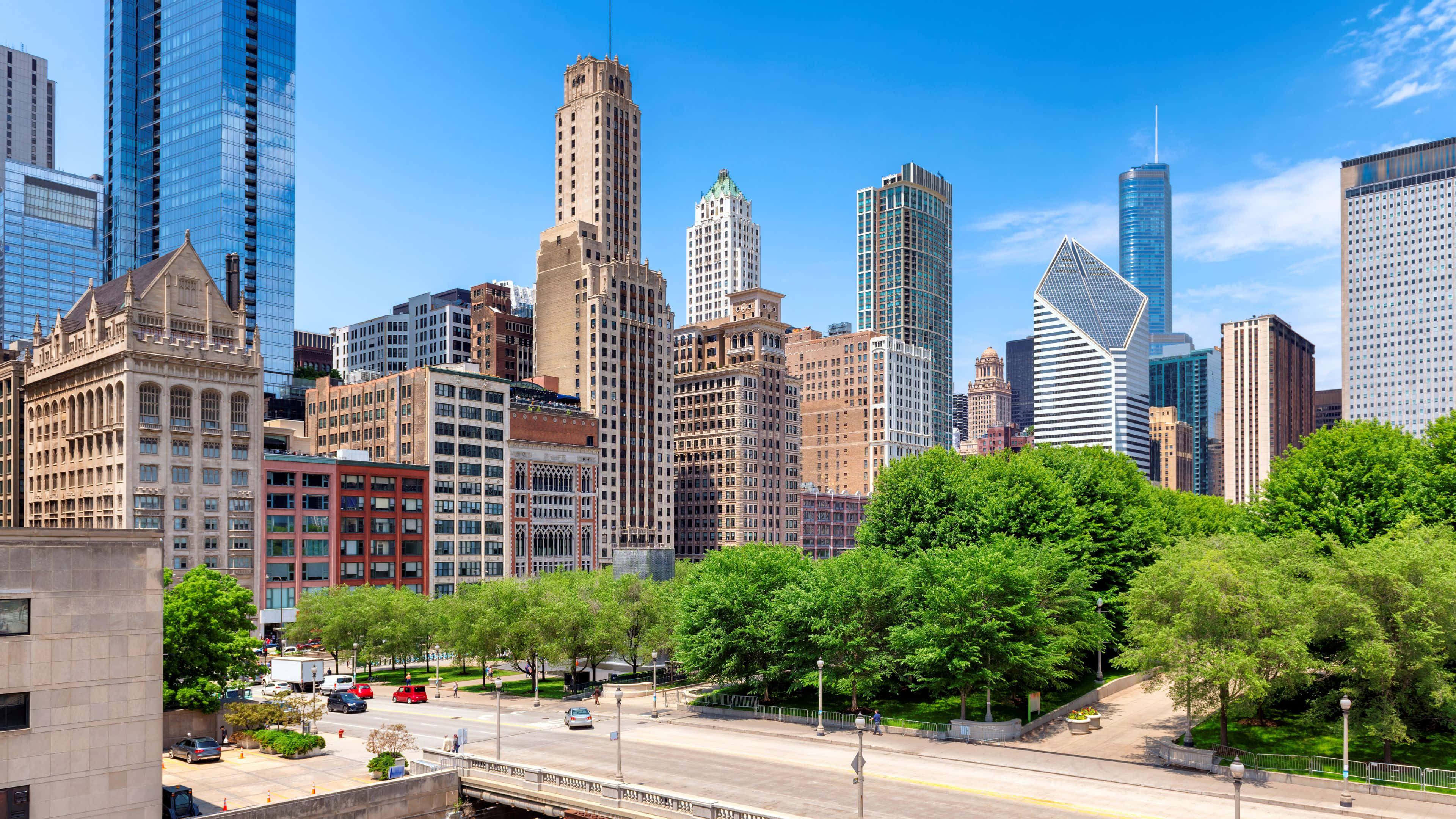 4K Ultra HD Chicago 桌布 壁紙 — 在晴朗的藍天下，充滿活力的城市景觀，高聳的摩天大樓和茂密的綠樹。