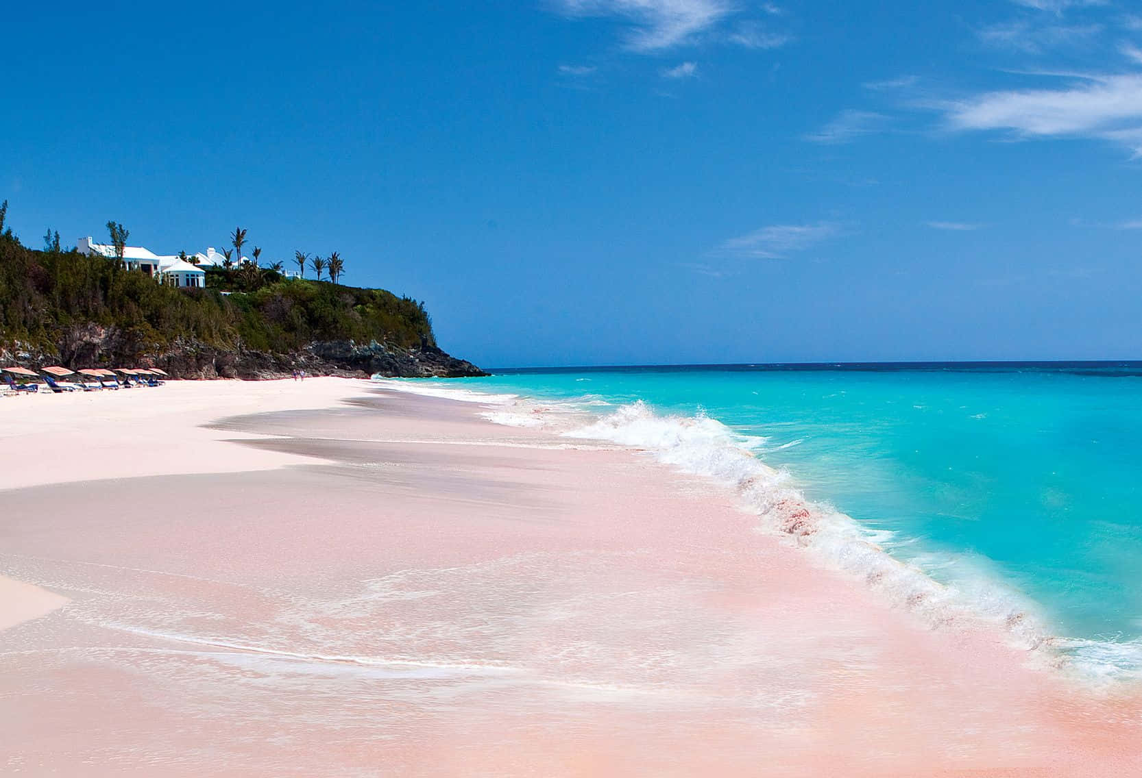 Pink Sand Beach 桌布 壁紙 — 在晴朗的藍天白雲下，一條迷人的粉紅色沙灘沿著碧綠的海水蜿蜒伸展。