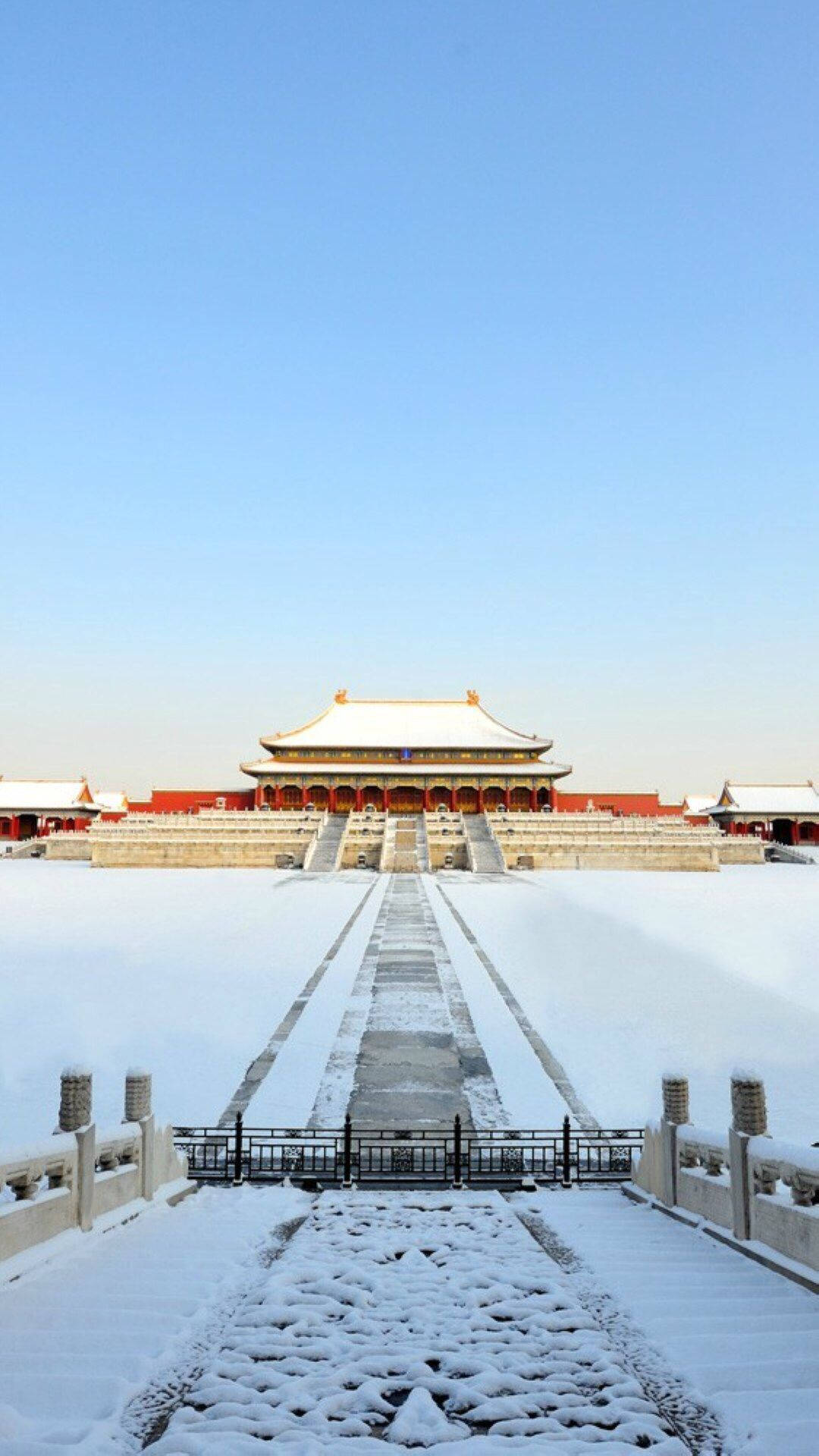  壁紙 — 在晴朗的藍色冬日天空下，一座被雪覆蓋的宏偉傳統中國宮殿。