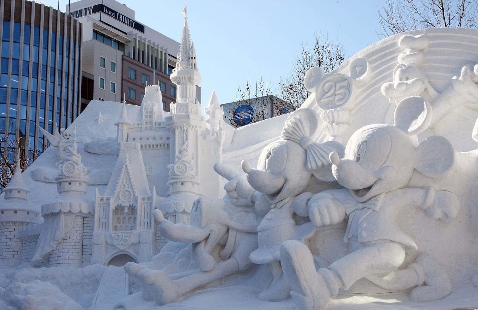Ice Sculpture 桌布 壁紙 — 在晴朗藍天下，一個詳細的雪雕，展示米奇和米妮老鼠在城堡旁邊，城堡上有 '25' 標誌。